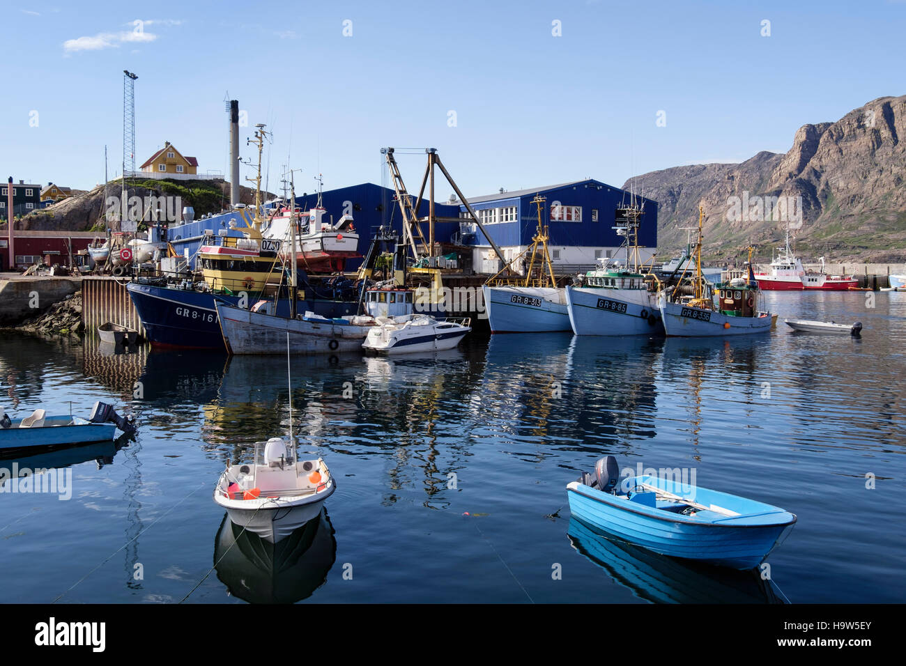Grönländische Angelboote/Fischerboote vertäut im Hafen mit Royal Greenland Fisch Fabrikgebäude hinter. Sisimiut Westgrönland Stockfoto