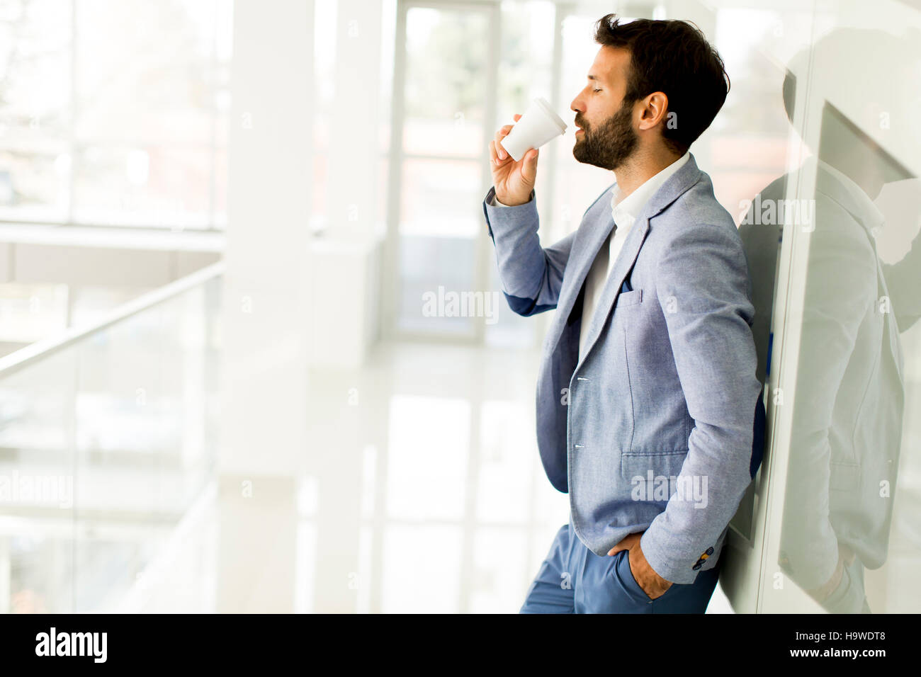 Geschäftsmann im Anzug mit Tasse Kaffee in einem Bürogebäude Stockfoto