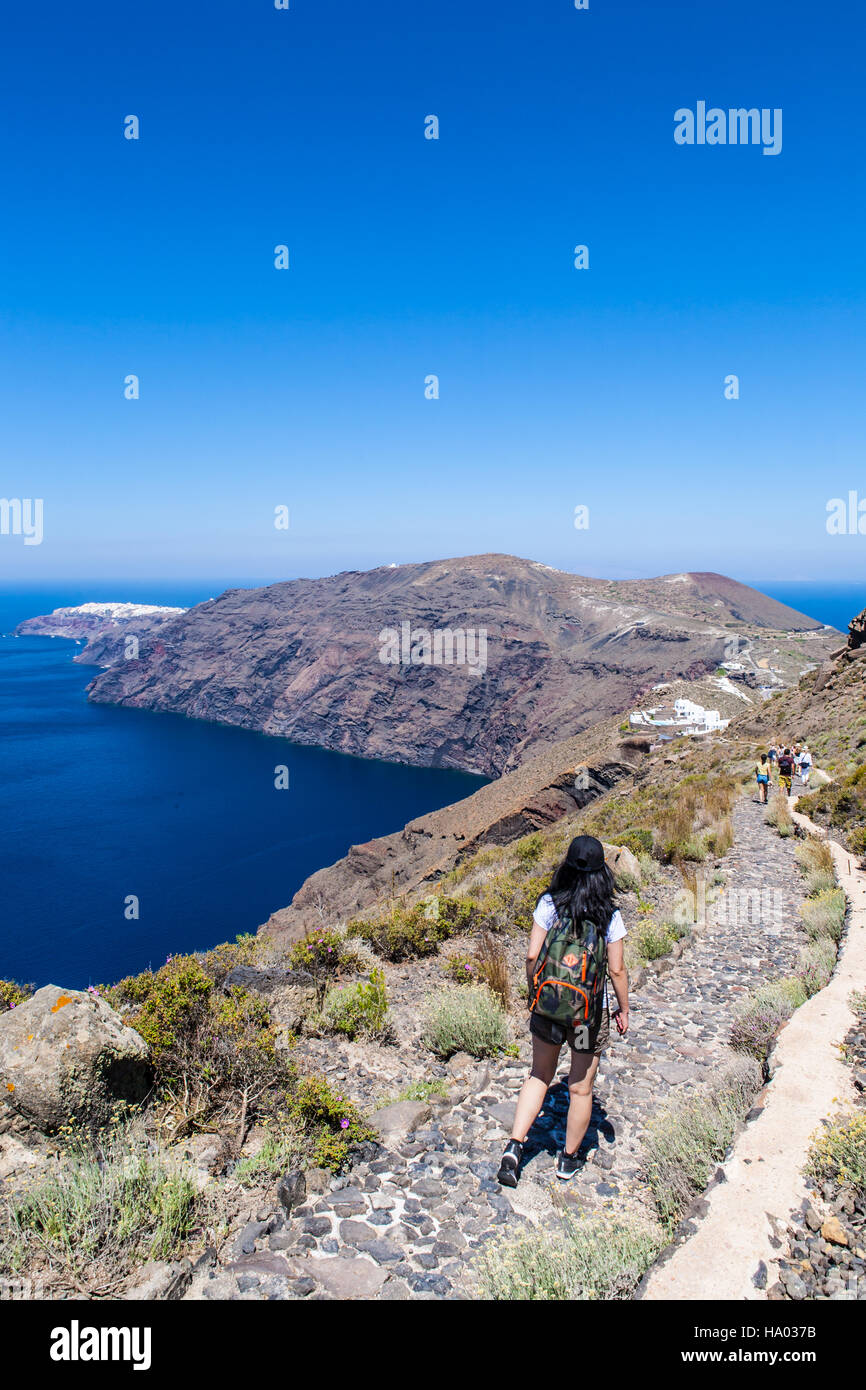 Junges Mädchen Wandern entlang des Randes der Vulkan von Fira nach Oia auf der griechischen Insel Santorini an einem warmen sonnigen Tag Stockfoto