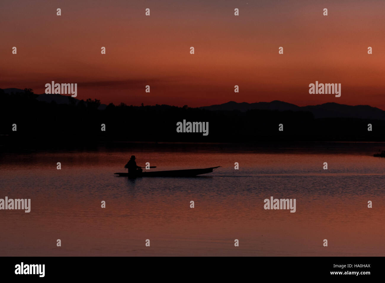 Silhouette eines Fischers auf Boot im See bei Sonnenuntergang, wunderschöne Landschaft. Stockfoto