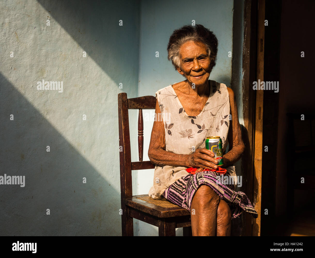Alten kubanischen Frau auf Stuhl genießen ein Bier Stockfoto