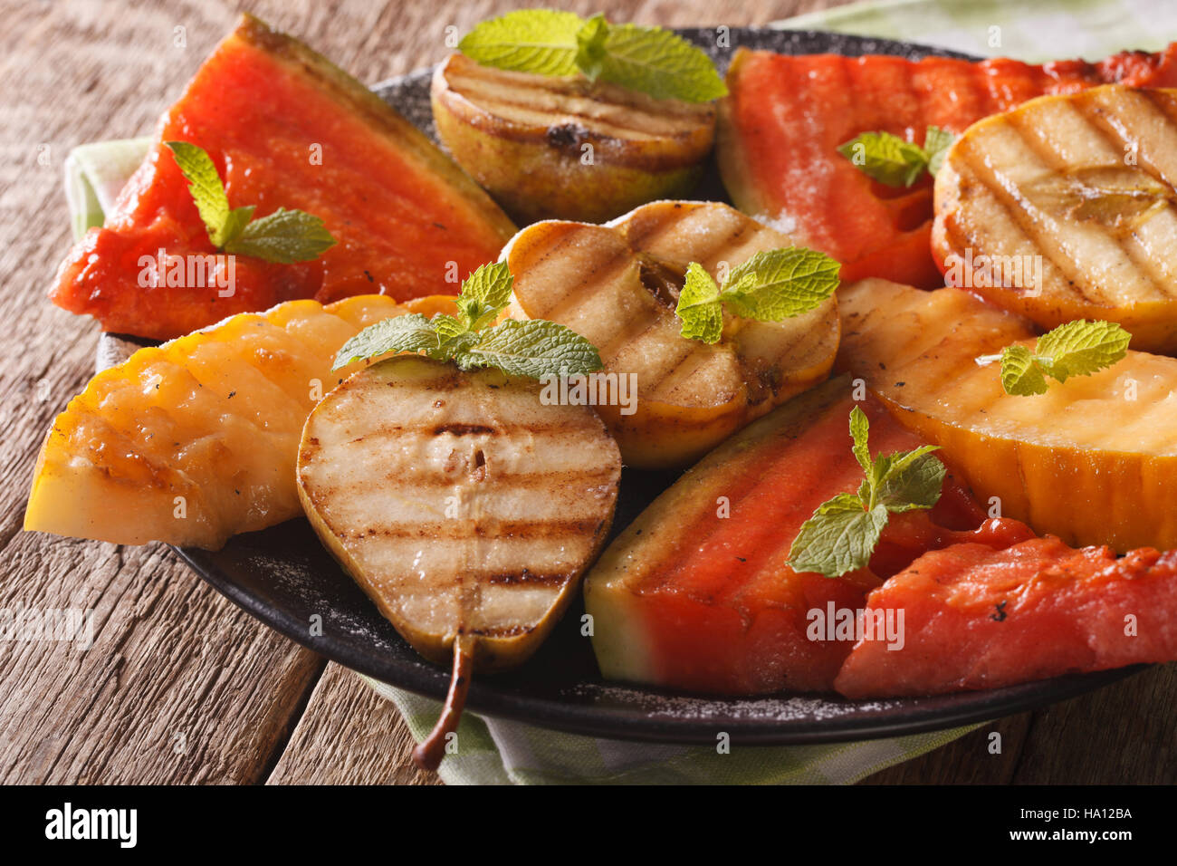Obst der Saison vom Grill, Wassermelone, Melone, Apfel, Birne mit Minze hautnah auf einem Teller. horizontale Stockfoto