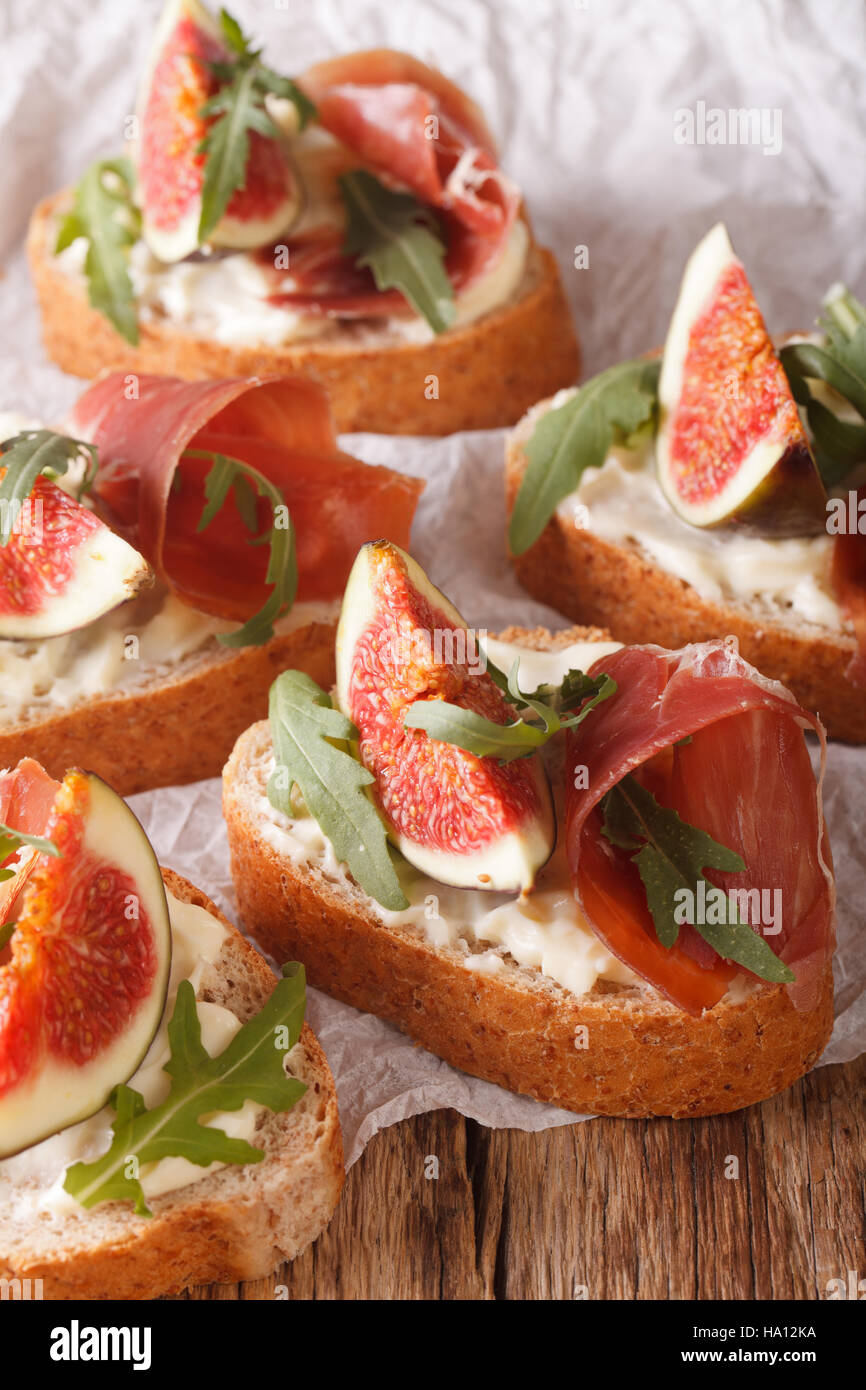 Gesunde Sandwiches mit Feigen, Parmaschinken, Rucola und Frischkäse-close-up auf dem Tisch. vertikale. rustikale Stockfoto