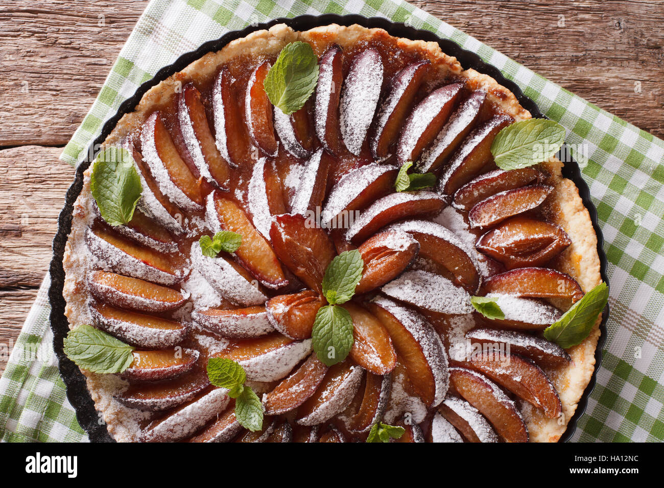 Leckere Kuchen: Pflaumen-Tarte mit Minze und Puderzucker Nahaufnahme auf dem Tisch. Horizontale Ansicht von oben Stockfoto