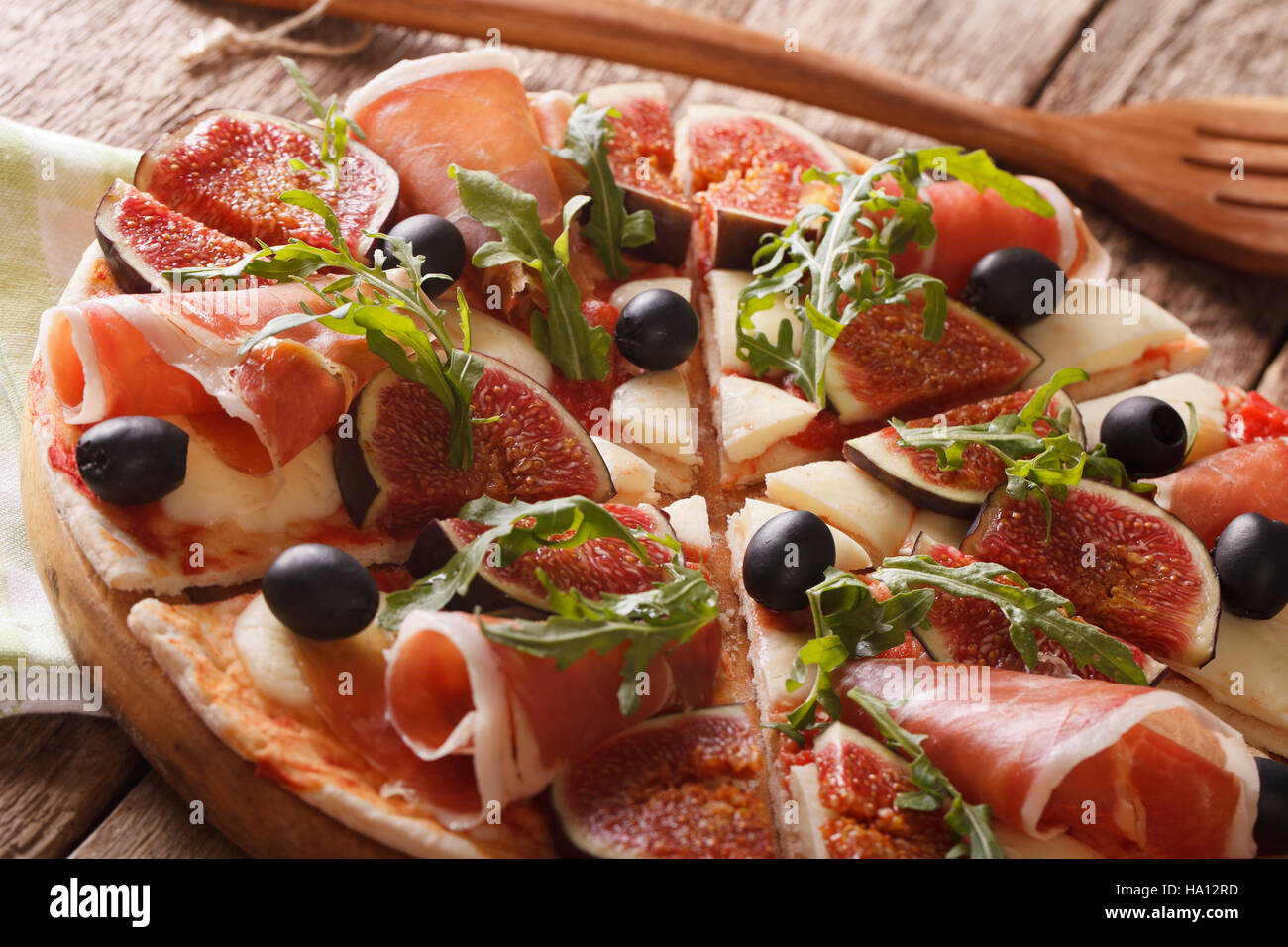 Pizza mit Feigen, Parmaschinken, Rucola, Oliven und Mozzarella-Käse-Makro auf dem Tisch. Horizontale Stockfoto