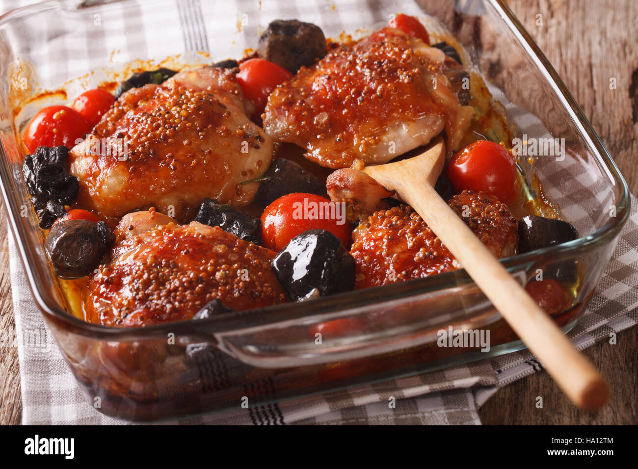 Leckeres Essen: Hühnerkeule gebacken mit Tomaten und Pilzen hautnah in Auflaufform auf den Tisch. horizontale Stockfoto