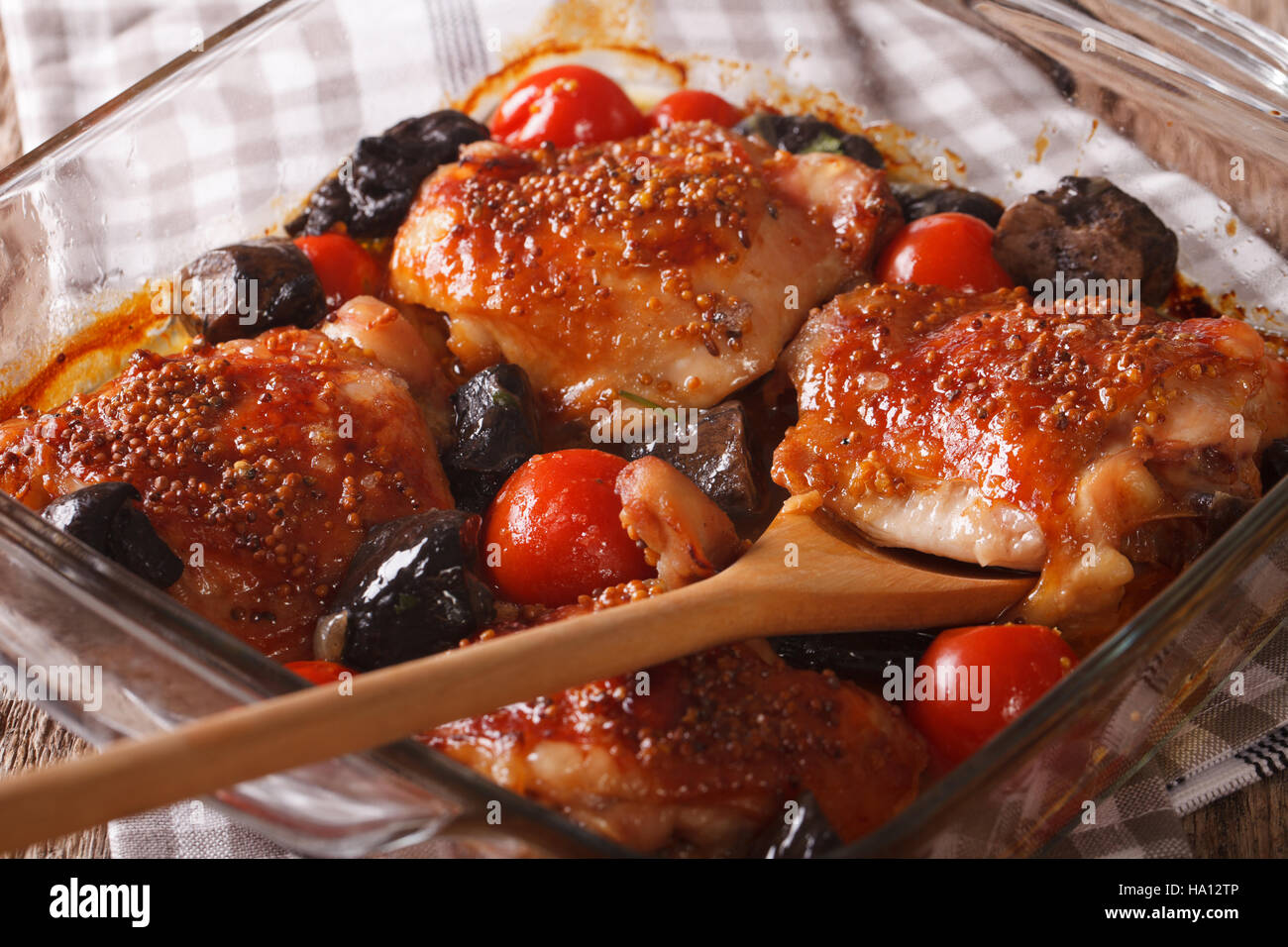 Hühnerkeule gebacken mit Tomaten und Steinpilzen hautnah in Auflaufform auf den Tisch. Horizontale Stockfoto