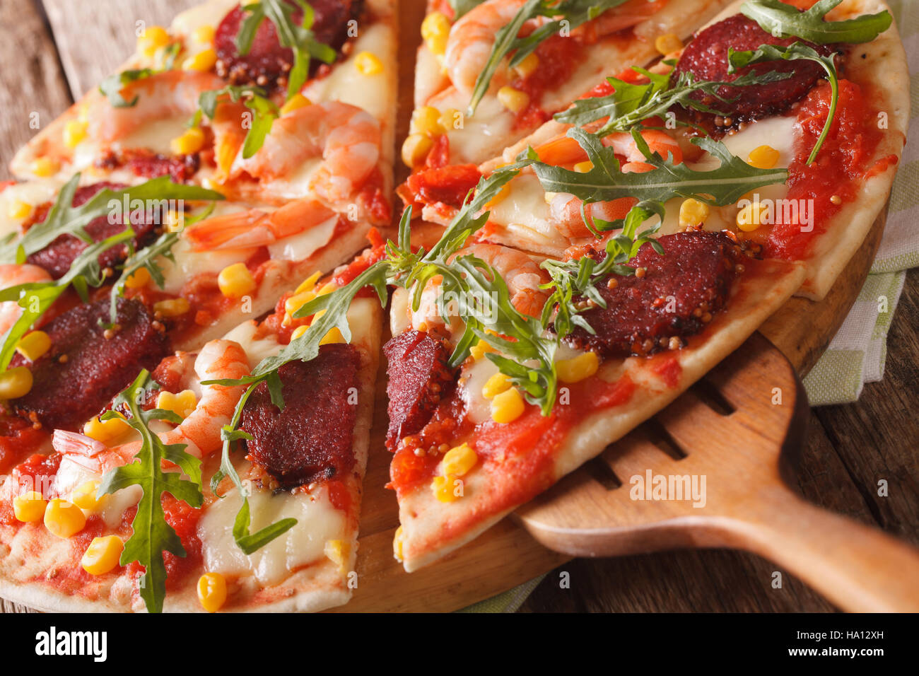 Pizza mit Shrimps, Salami, Käse und Rucola Makro auf einem Holzbrett. horizontale Stockfoto