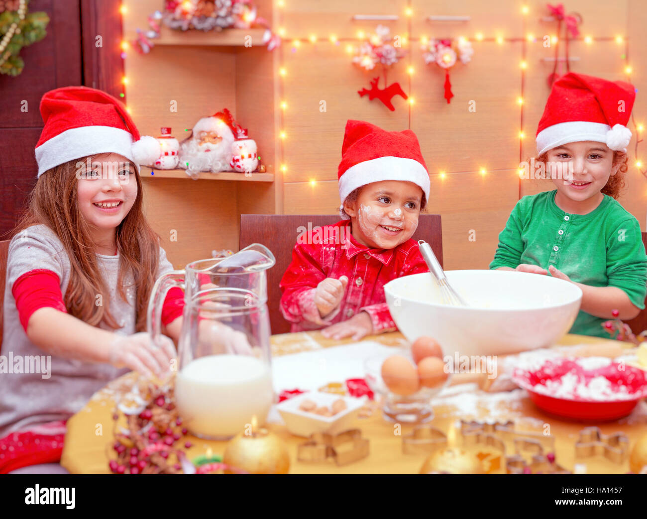 Glückliche Kinder Weihnachtskekse zu Hause machen, Kinder drei süße kleine tragen rote Santa Hüte festliche leckeren Bonbons, traditionelle Feier vorbereiten Stockfoto