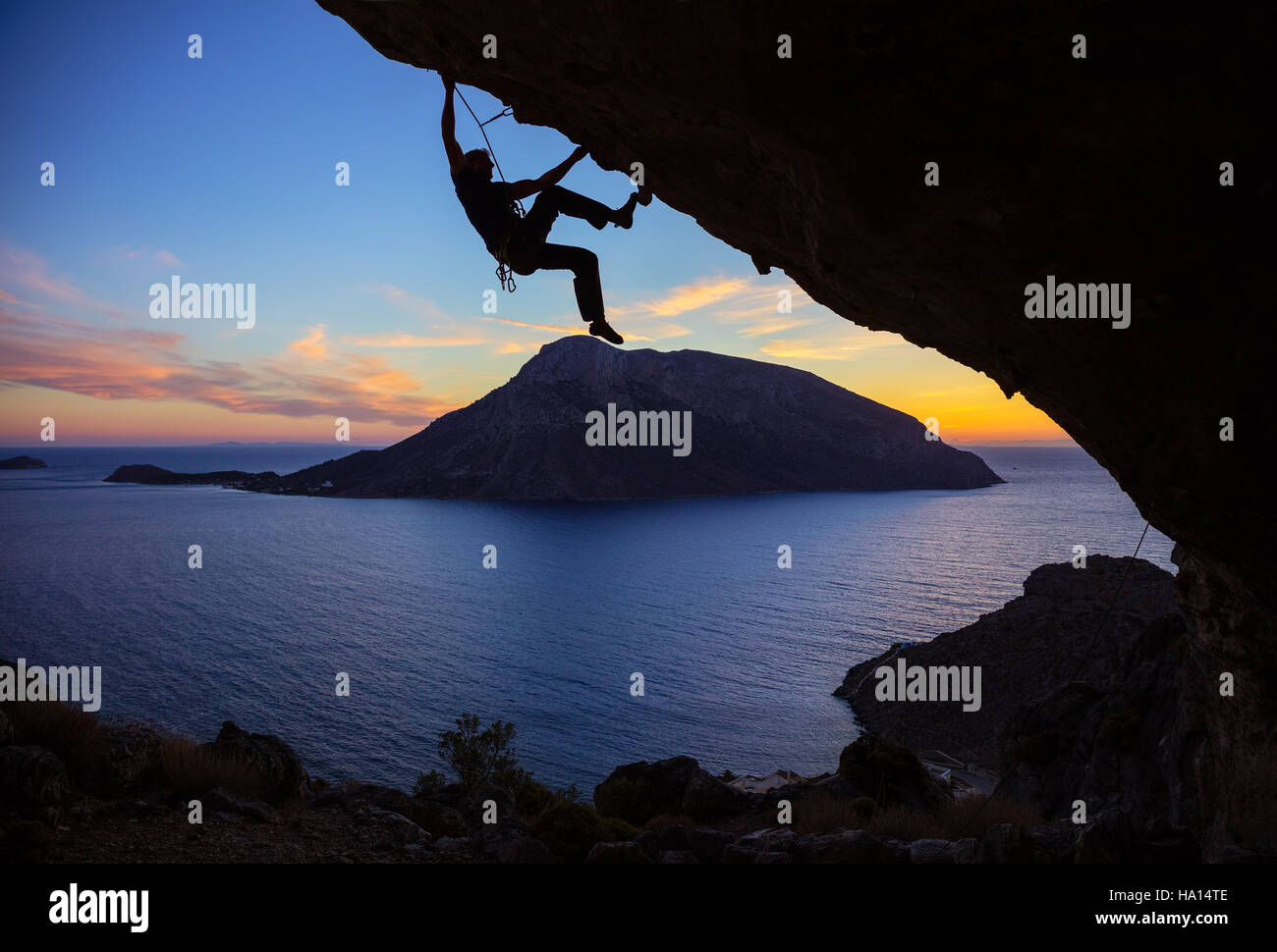 Junger Mann Klettern entlang Dach in Höhle bei Sonnenuntergang Stockfoto