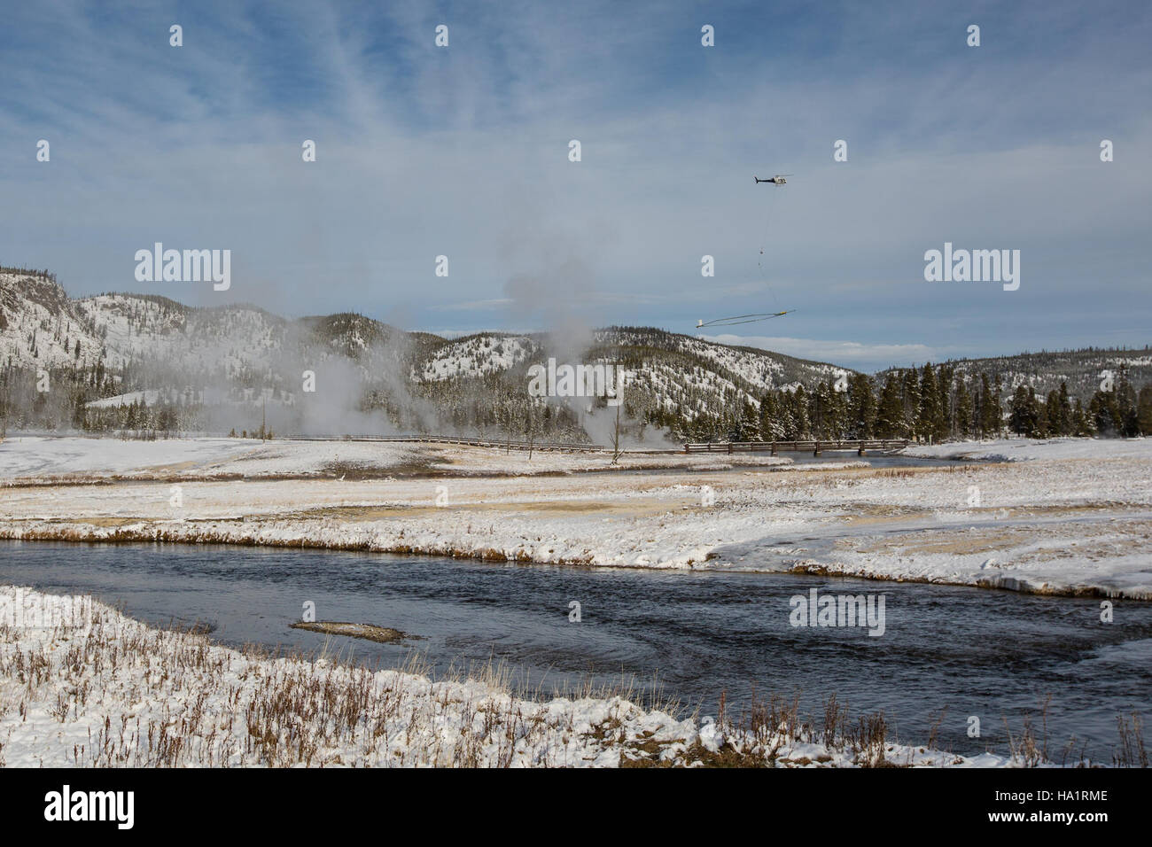 Ein Hubschrauber fliegt über das Biscuit Basin im Yellowstone-Nationalpark. Ziel der Untersuchung ist es, geophysikalische Daten zu sammeln, um die geothermische Aktivität und ihre Auswirkungen auf die Umwelt besser zu verstehen. Stockfoto