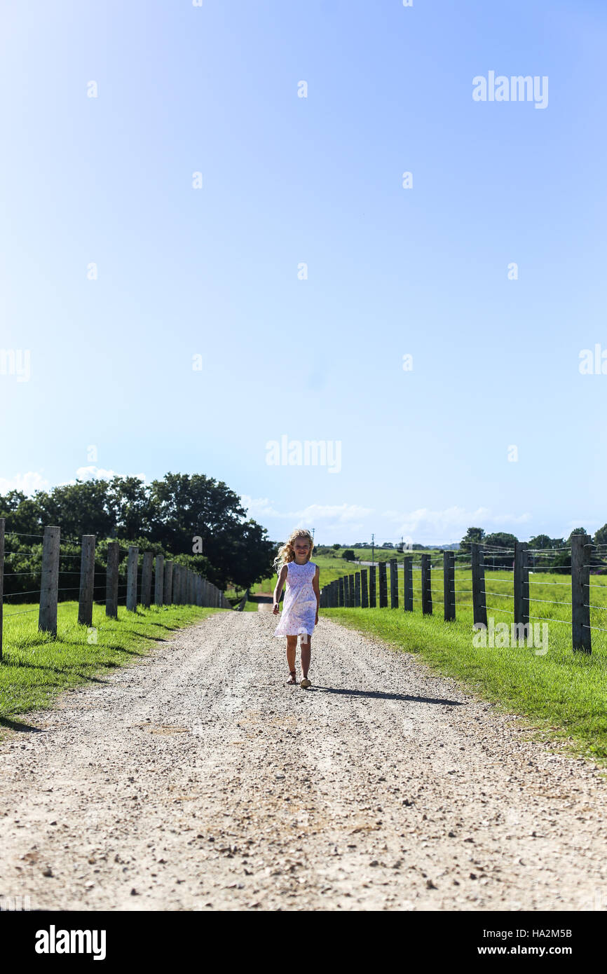 Mädchen zu Fuß entlang der Landstraße Stockfoto