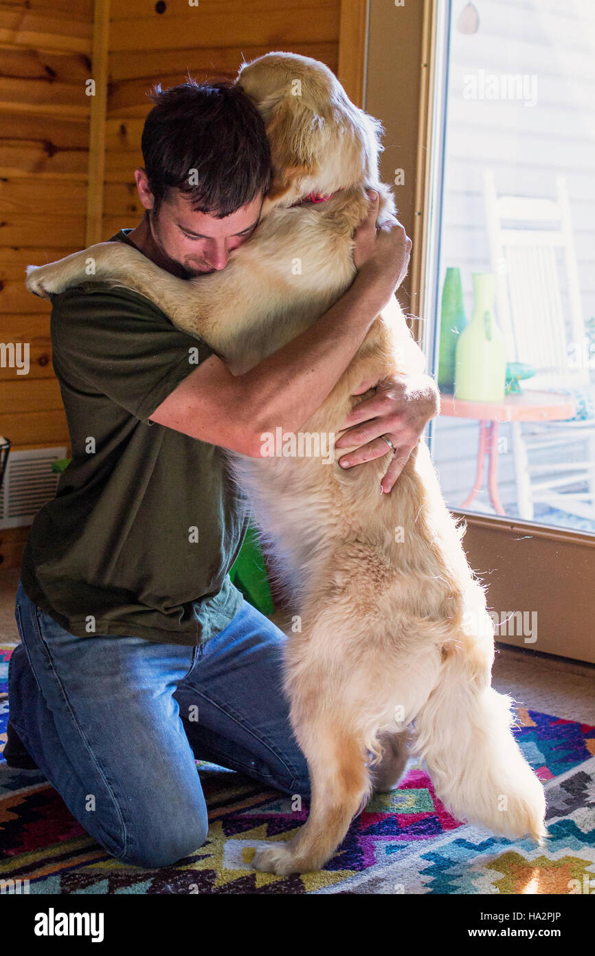 Mann umarmt Golden Retriever Hund Stockfoto