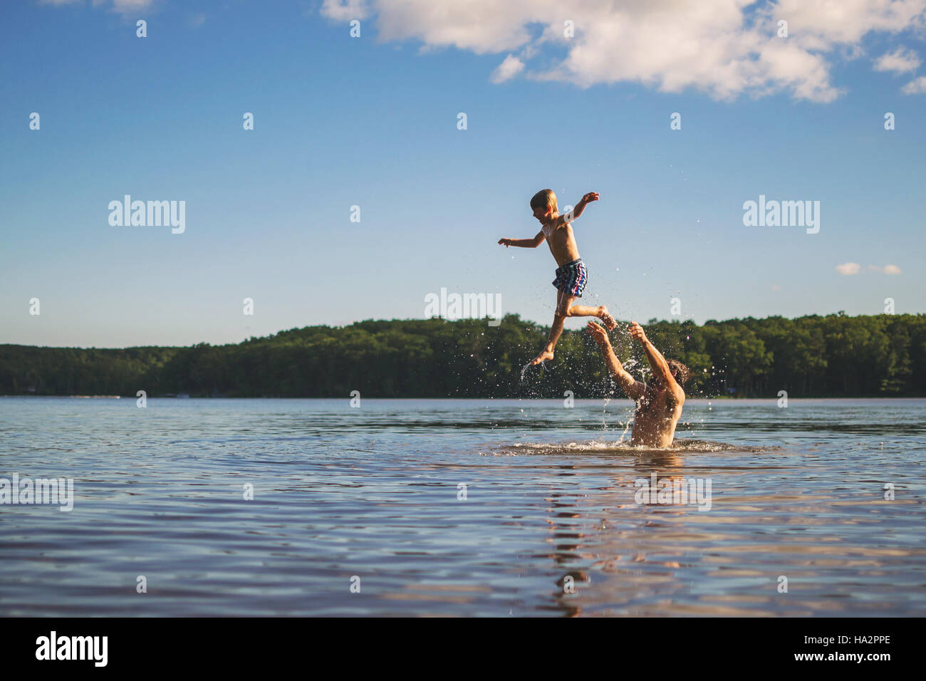 Vater Sohn in der Luft stehend in einem See zu werfen Stockfoto