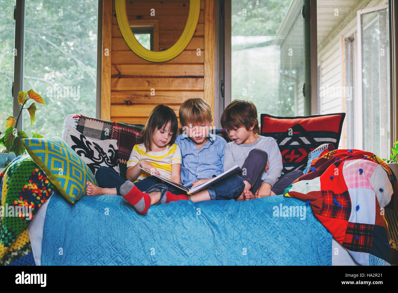 Drei Kinder sitzen auf der Couch lesen Stockfoto