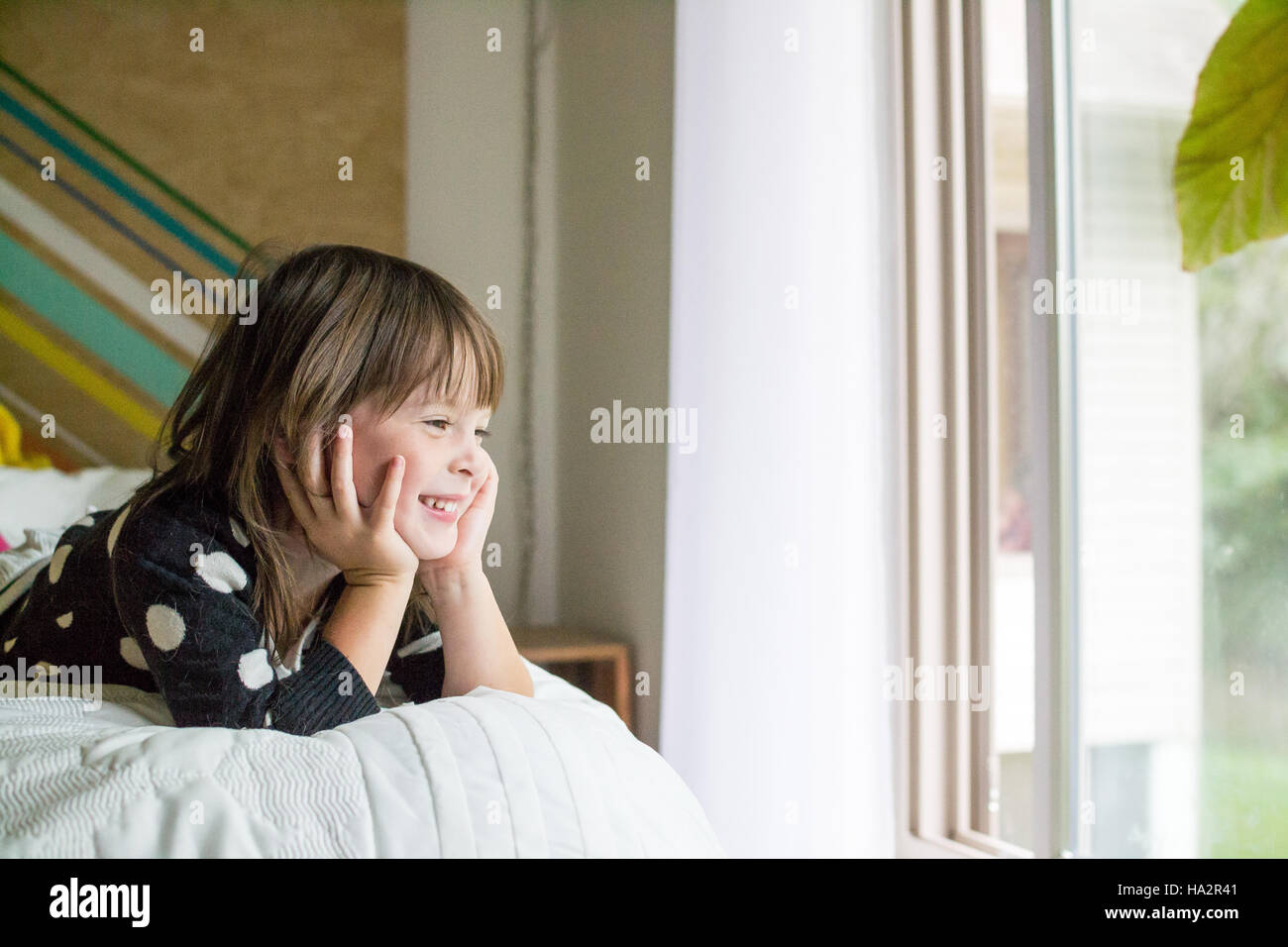 Porträt eines lächelnden Mädchens auf einem Bett liegend Stockfoto