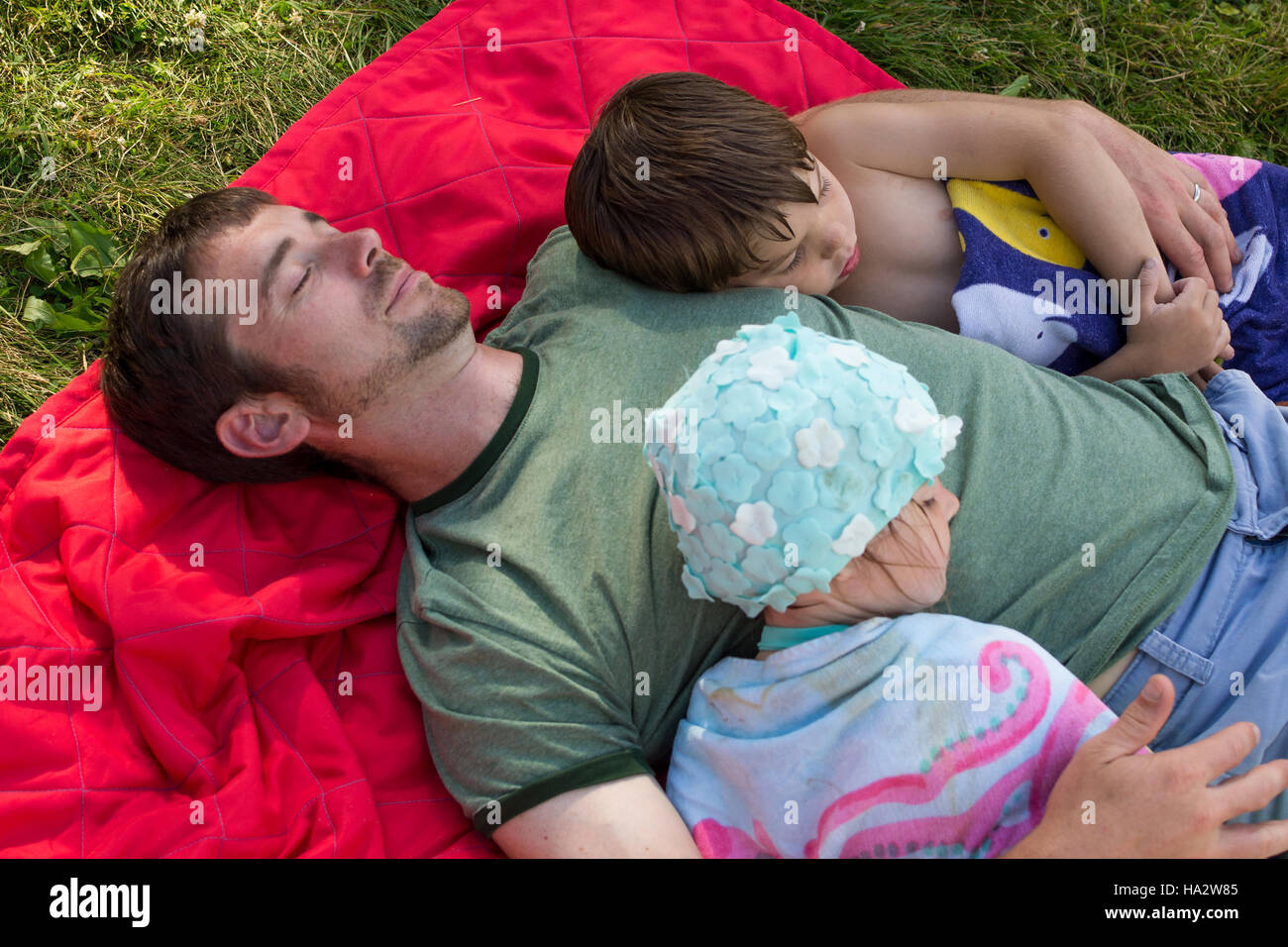 Vater und zwei Kinder schlafen auf der Picknickdecke Stockfoto