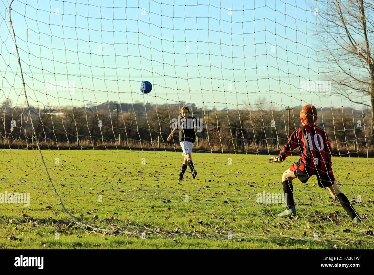 Mädchen und Jungen spielen Fußball auf einem englischen Schule Feld Stockfoto