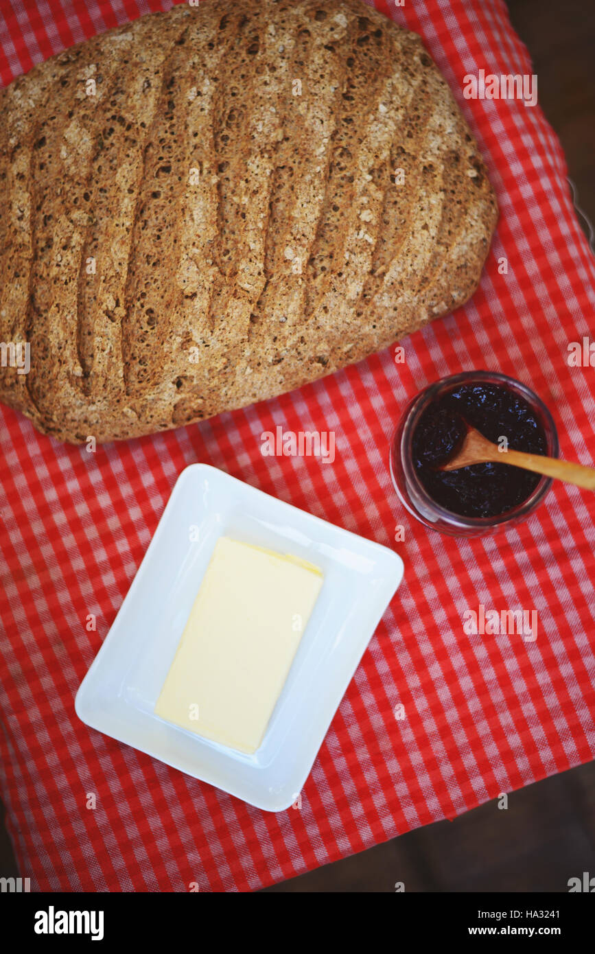 Frisch gebackenes Brot auf Tartan Tabellenhintergrund mit Butter und Himbeermarmelade Stockfoto