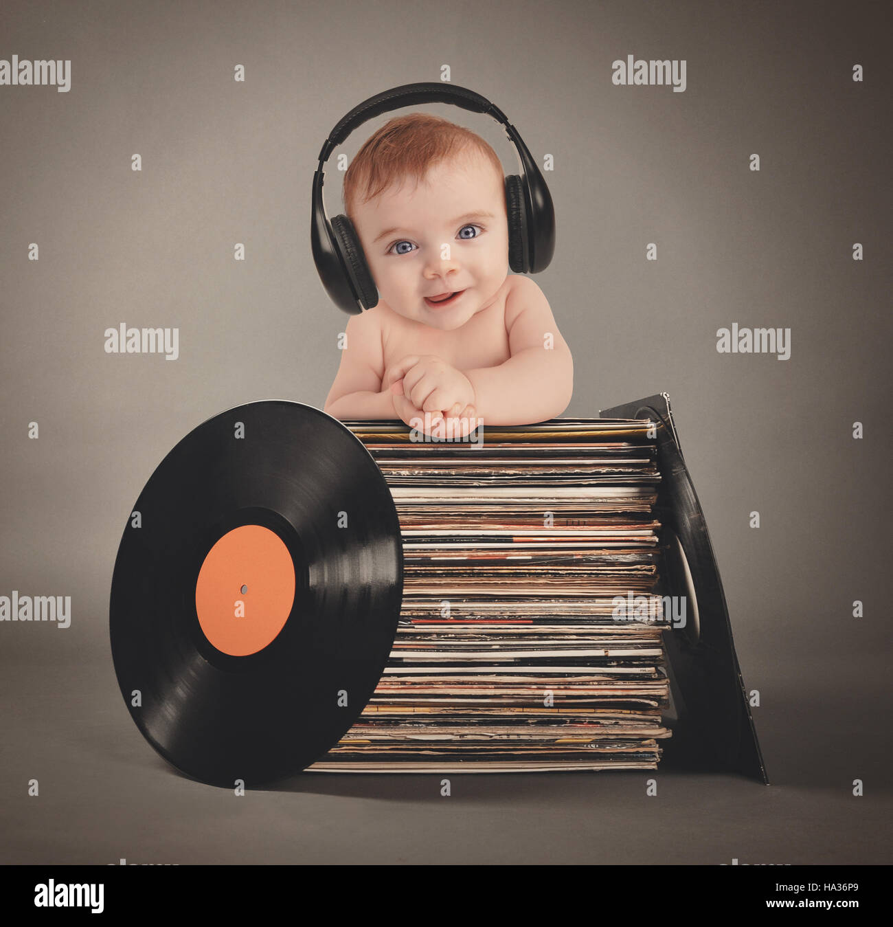 Ein kleines Baby trägt Musik Kopfhörer mit retro-Vinyl-Platten auf einem  isolierten grauen Hintergrund für eine Partei oder Entertainment-Konzept  Stockfotografie - Alamy