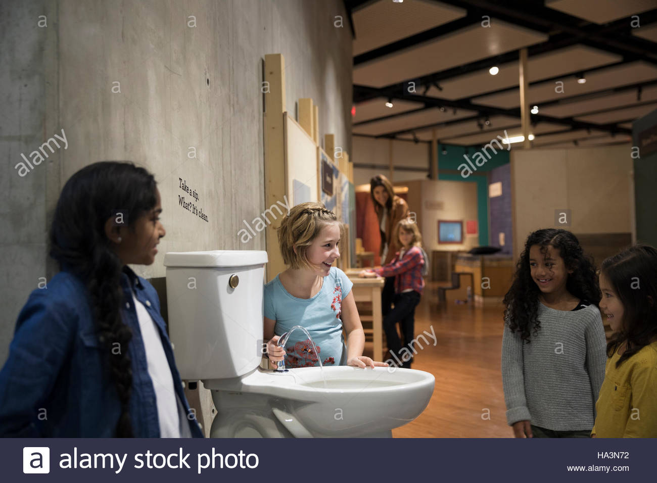 Mädchen trinken aus WC-Wasser-Brunnen im Science center Stockfoto