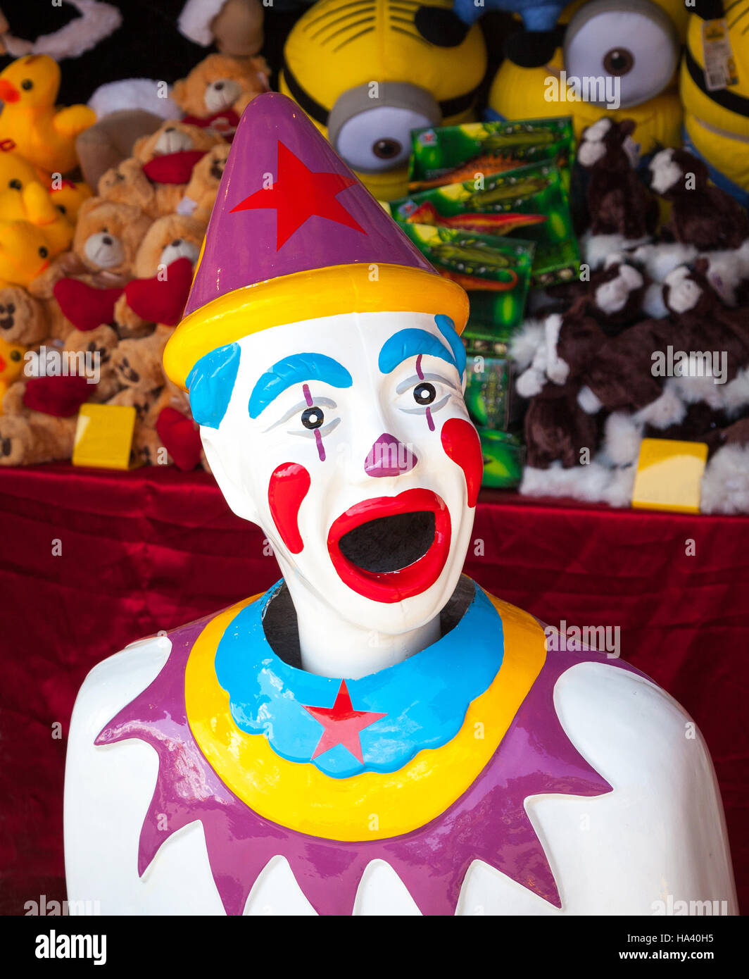 Ein bunte Arcade-Clown mit Preisen gestapelt hinter ihm. Stockfoto