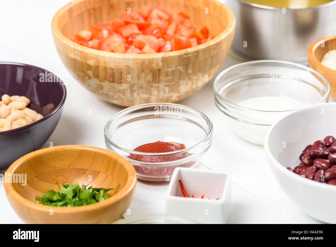 Weiße und rote Kidney-Bohnen, Paprika, Petersilie, Ketchup, Tomaten und Joghurt Lebensmittelzutaten auf weißem Holz Tisch Stockfoto