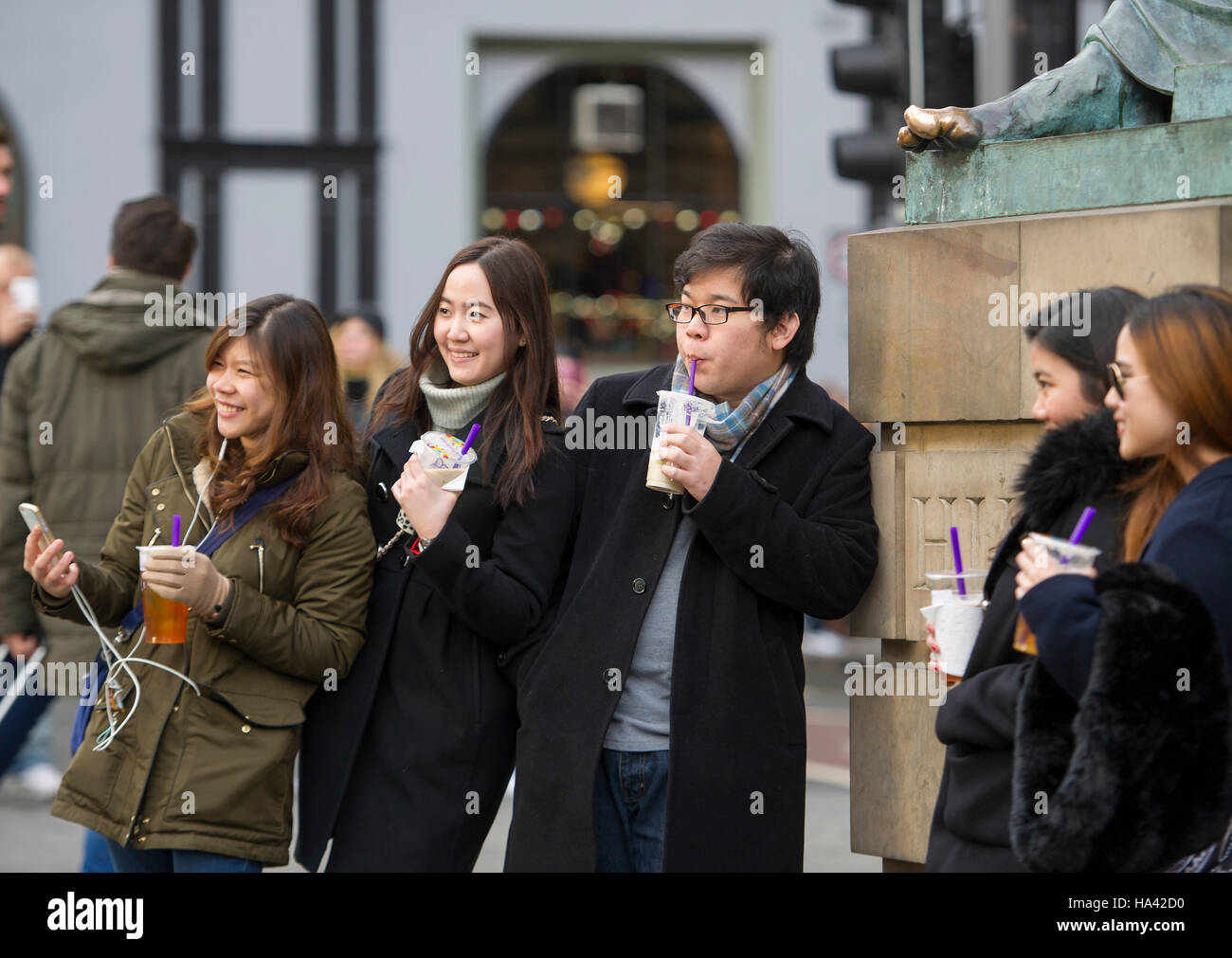Touristen posieren für Bilder an der Statue des Philosophen David Hume, der außerhalb der High Court auf Edinburghs Royal Mile sitzt. Stockfoto