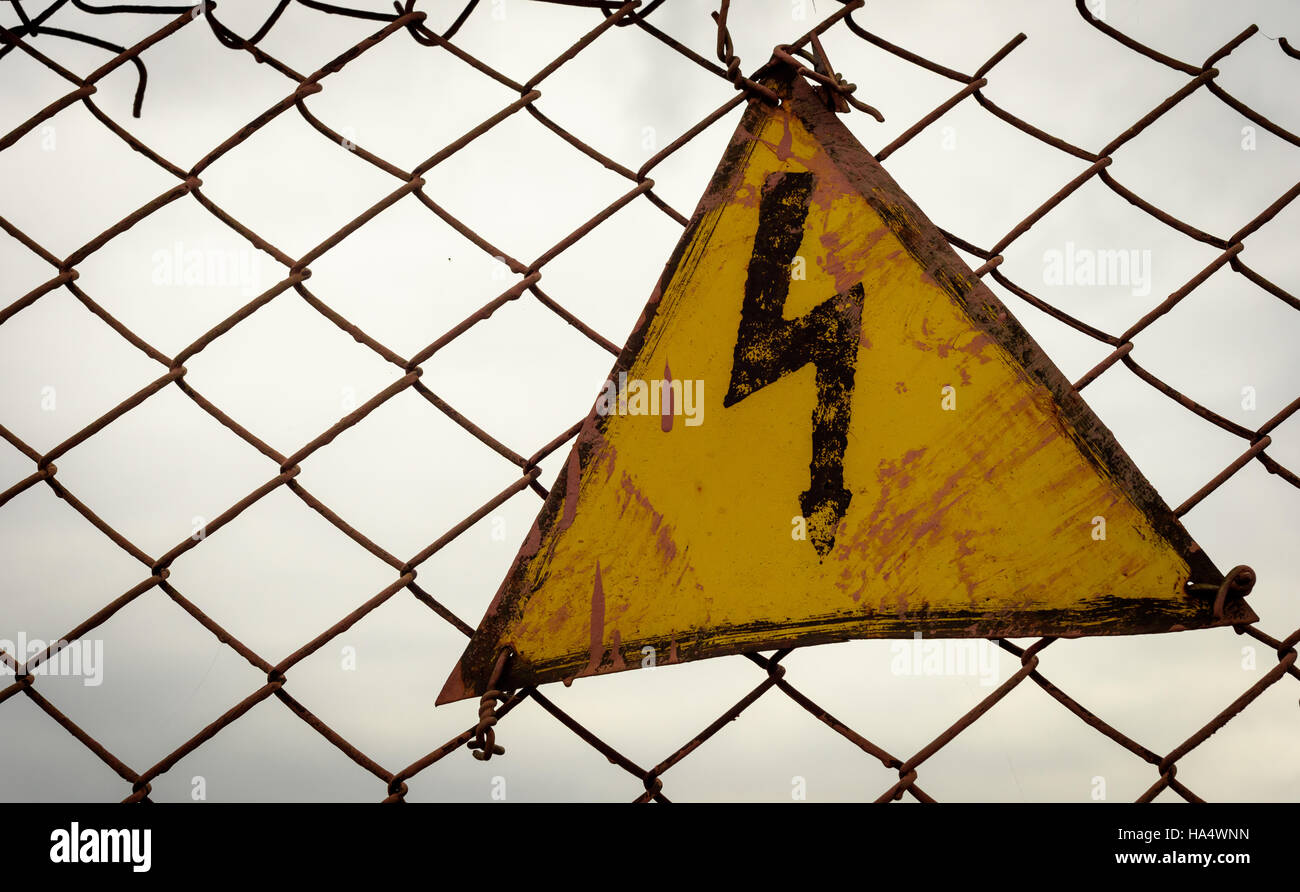 Lightning Bolt Strom Warnschild in einem gelben Dreieck vor einem dunklen Himmel Wire Mesh Hintergrund festlegen Stockfoto