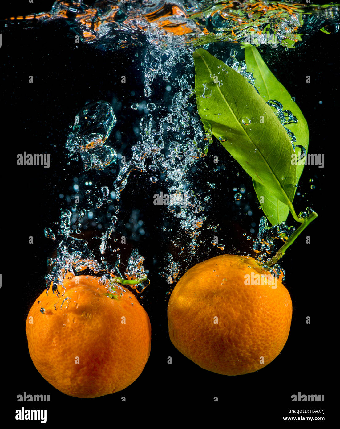 Orangen und Mandarinen in Wasser mit Luftblasen. Stockfoto