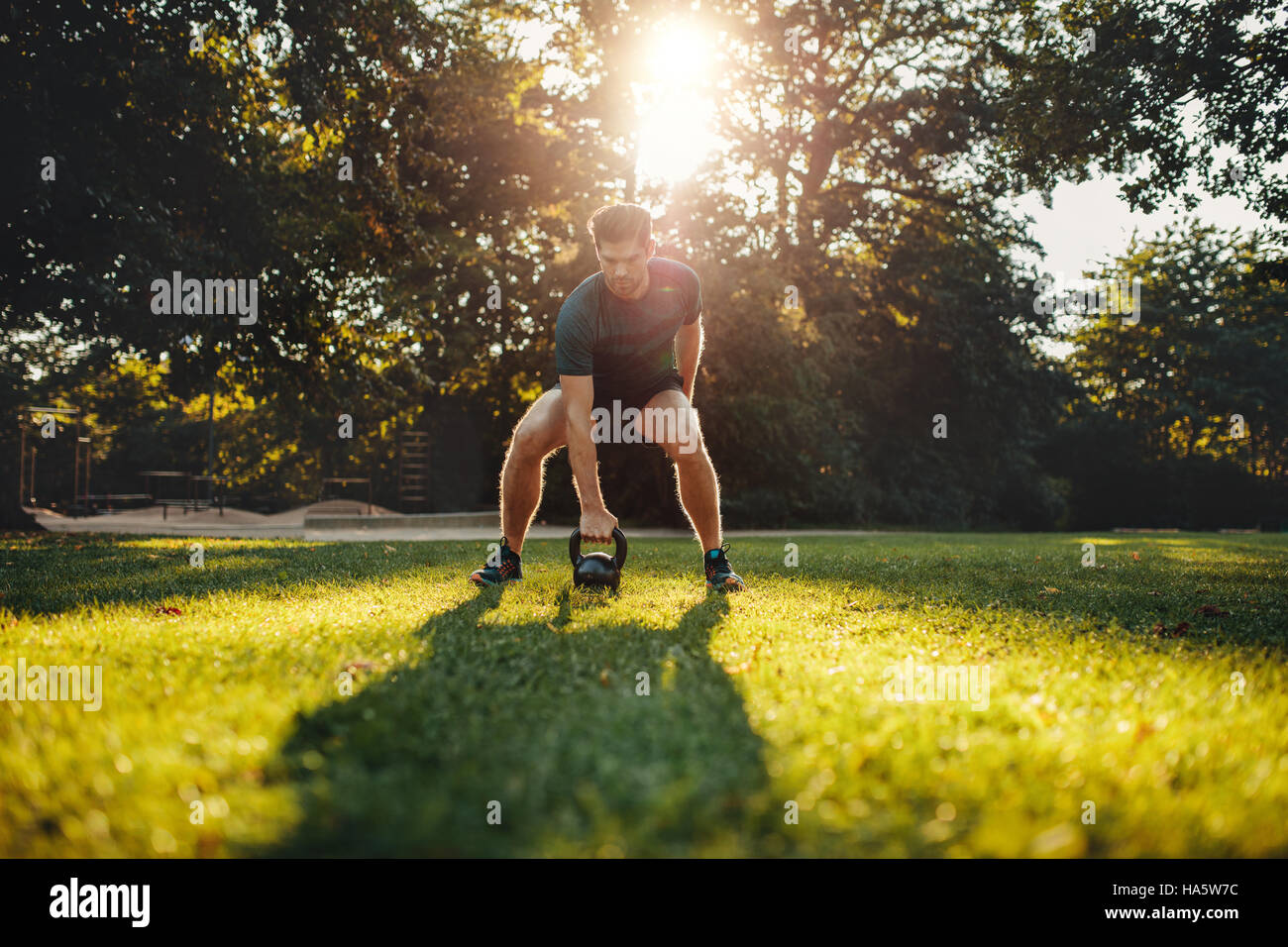 Schuss von Fit junger Mann Training mit Kettlebell draußen im Park.  Starker junger Mann im Park Morgen training. Stockfoto