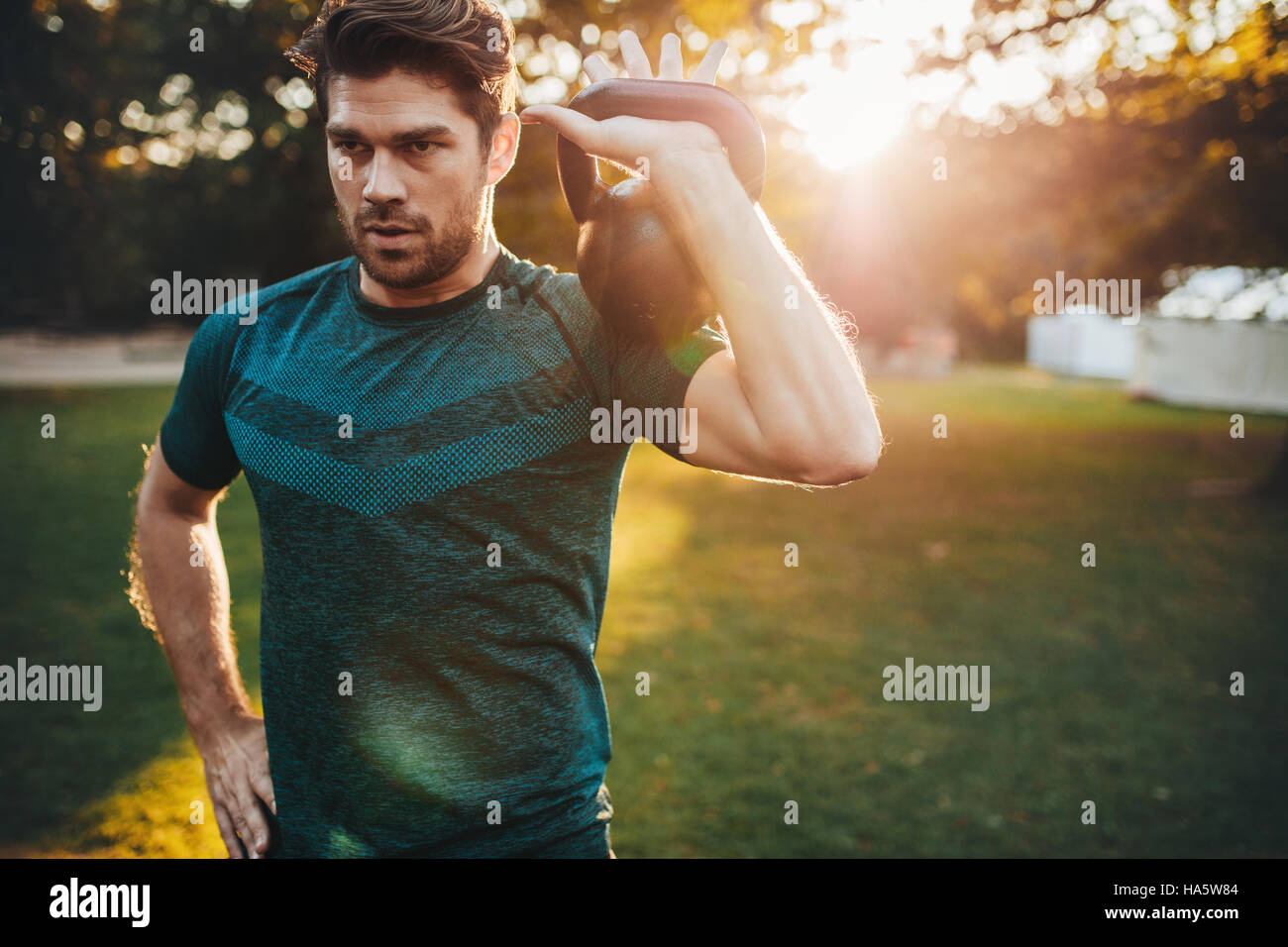 Schuss von Fit junger Mann Training mit Kettlebell in den Park.  Starker junger Mann im Park Morgen training. Stockfoto