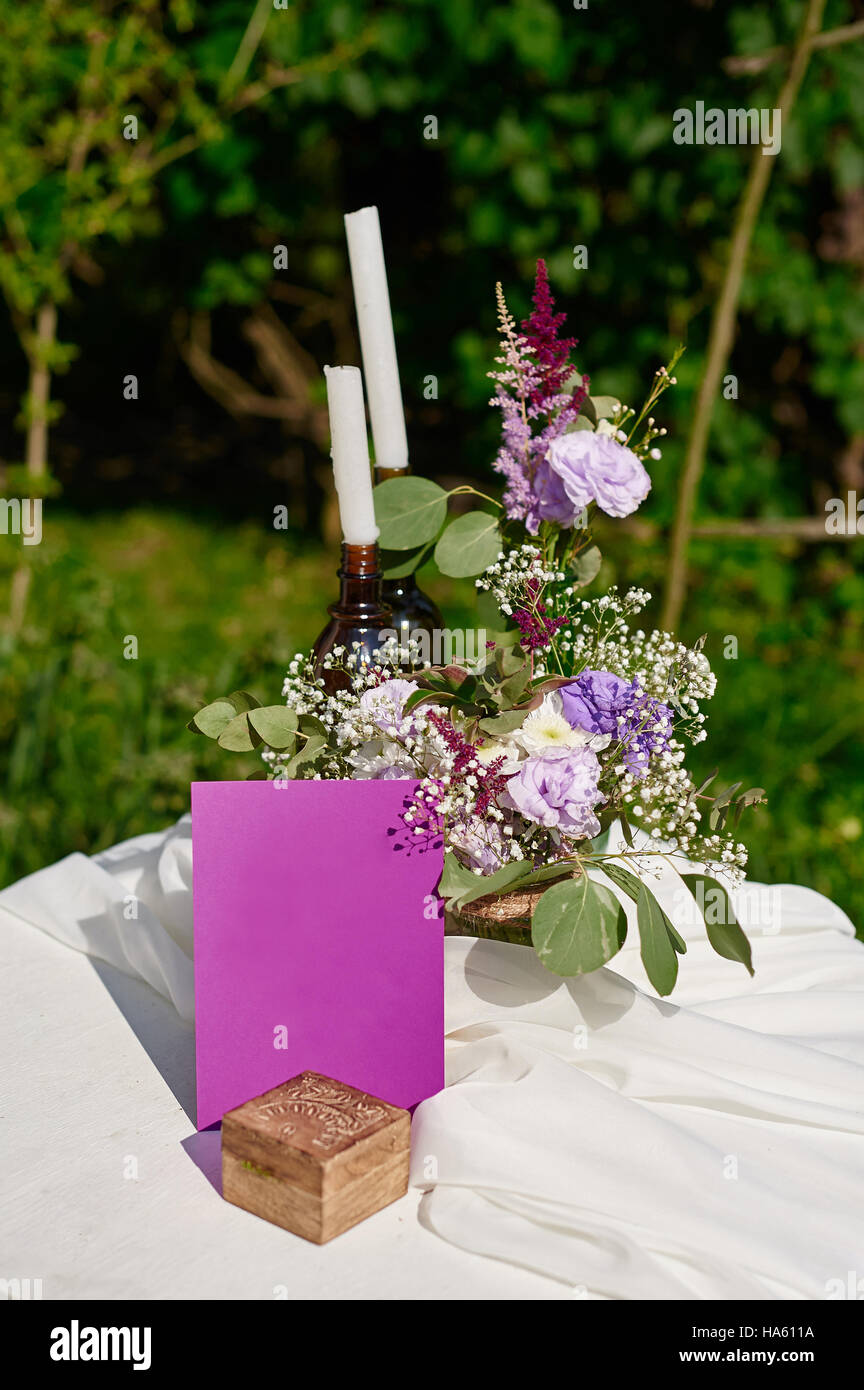 Blumenstrauß und zwei Kerzen auf dem Tisch für eine Trauung im Park Stockfoto