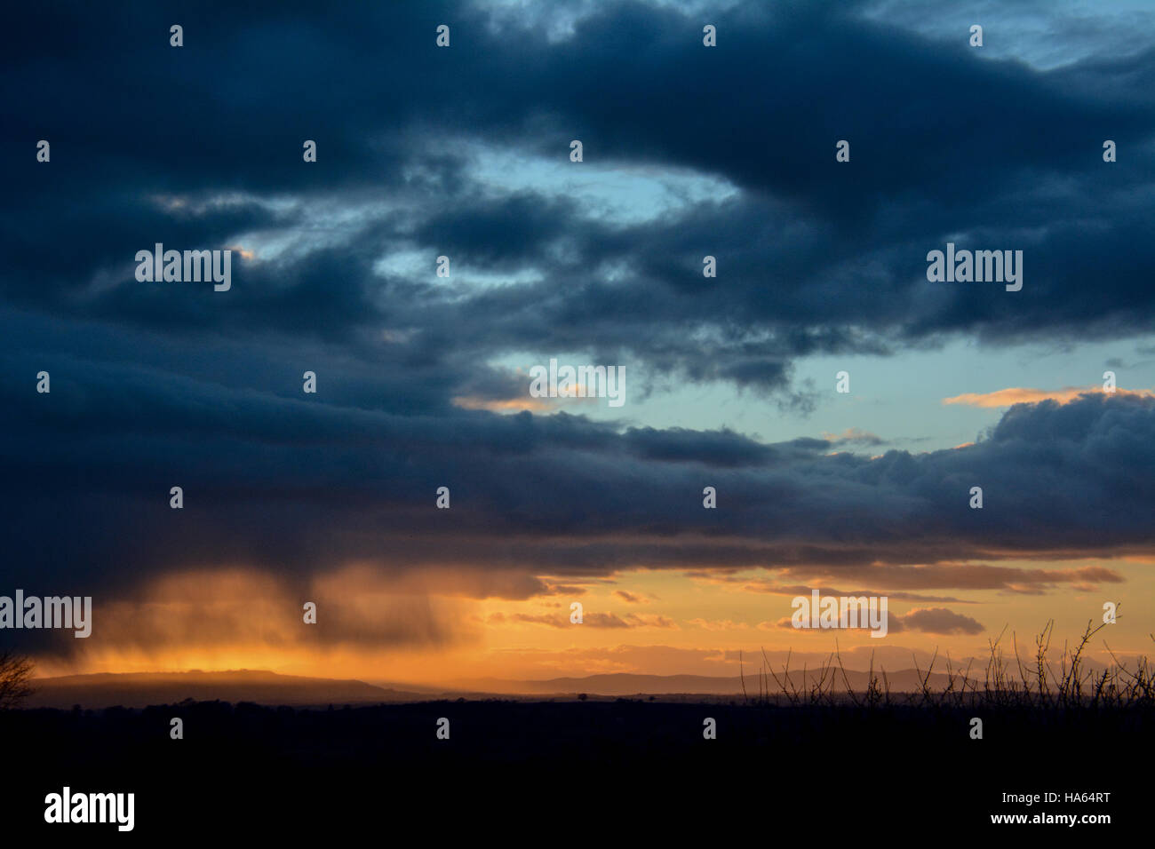 Dramatische Cotswolds Winter Szene graue Wolken und strahlend blauer Himmel mit Cirrus Sonnenuntergang Stockfoto