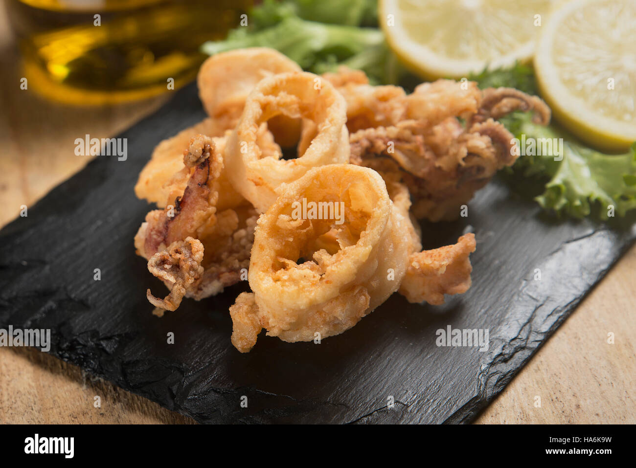 knusprig gebratenen Calamari auf Schiefer Teller serviert Stockfoto