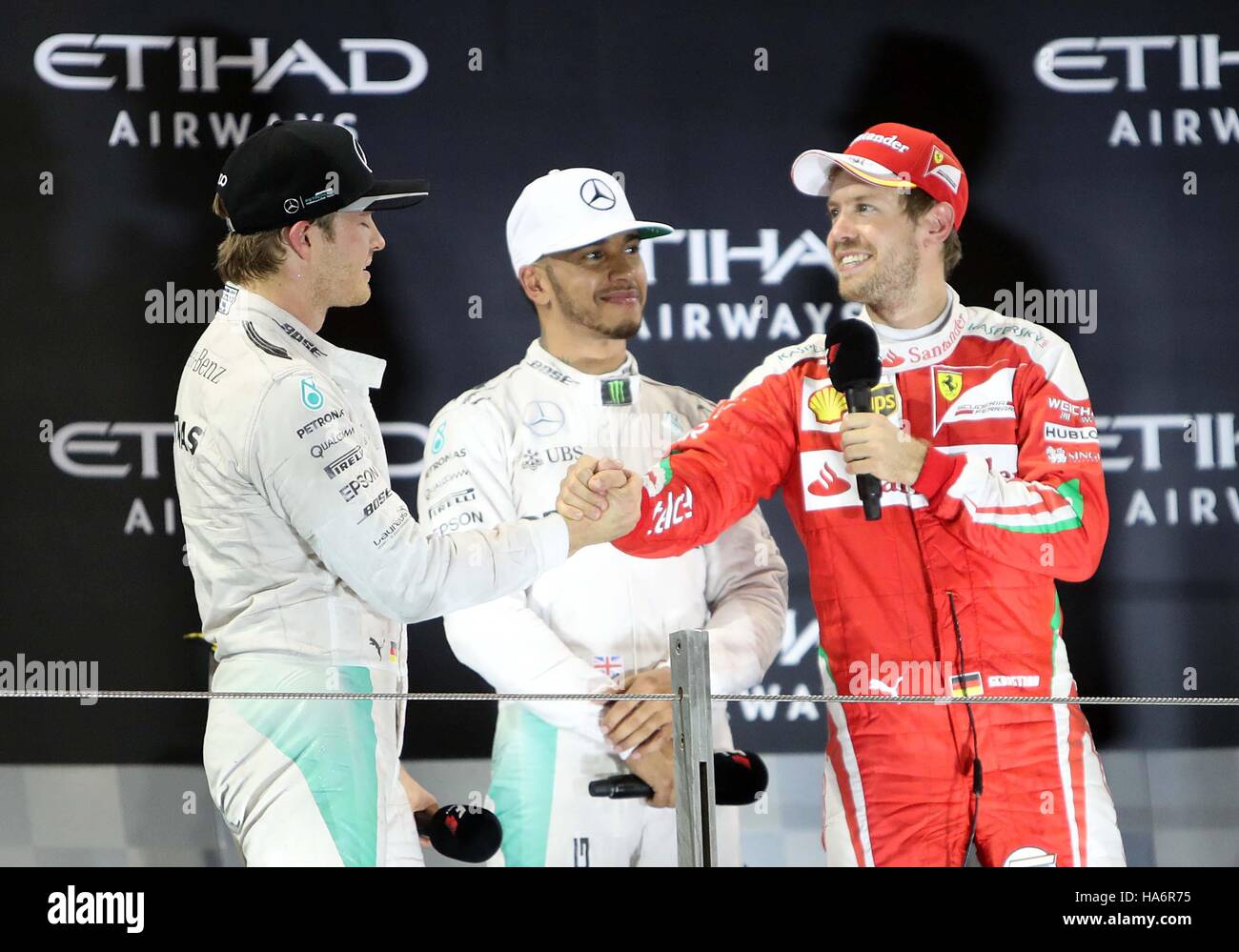 Mercedes' Nico Rosberg (links) schüttelt Hände mit Sebastian Vettel, Lewis Hamilton (Mitte), beobachtete, wie er feiert die Formel1-Weltmeisterschaft zu gewinnen, während des Grand Prix von Abu Dhabi auf dem Yas Marina Circuit, Abu Dhabi. Stockfoto