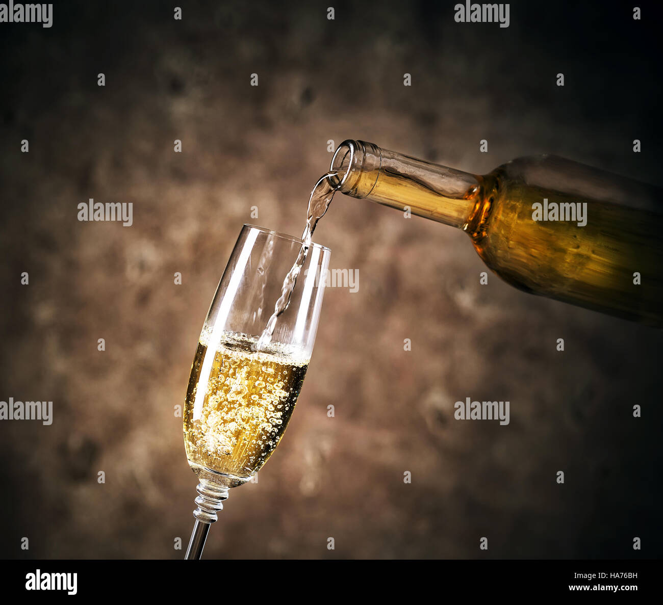 Weißwein in ein Glas gießen auf dunklem Hintergrund Stockfoto