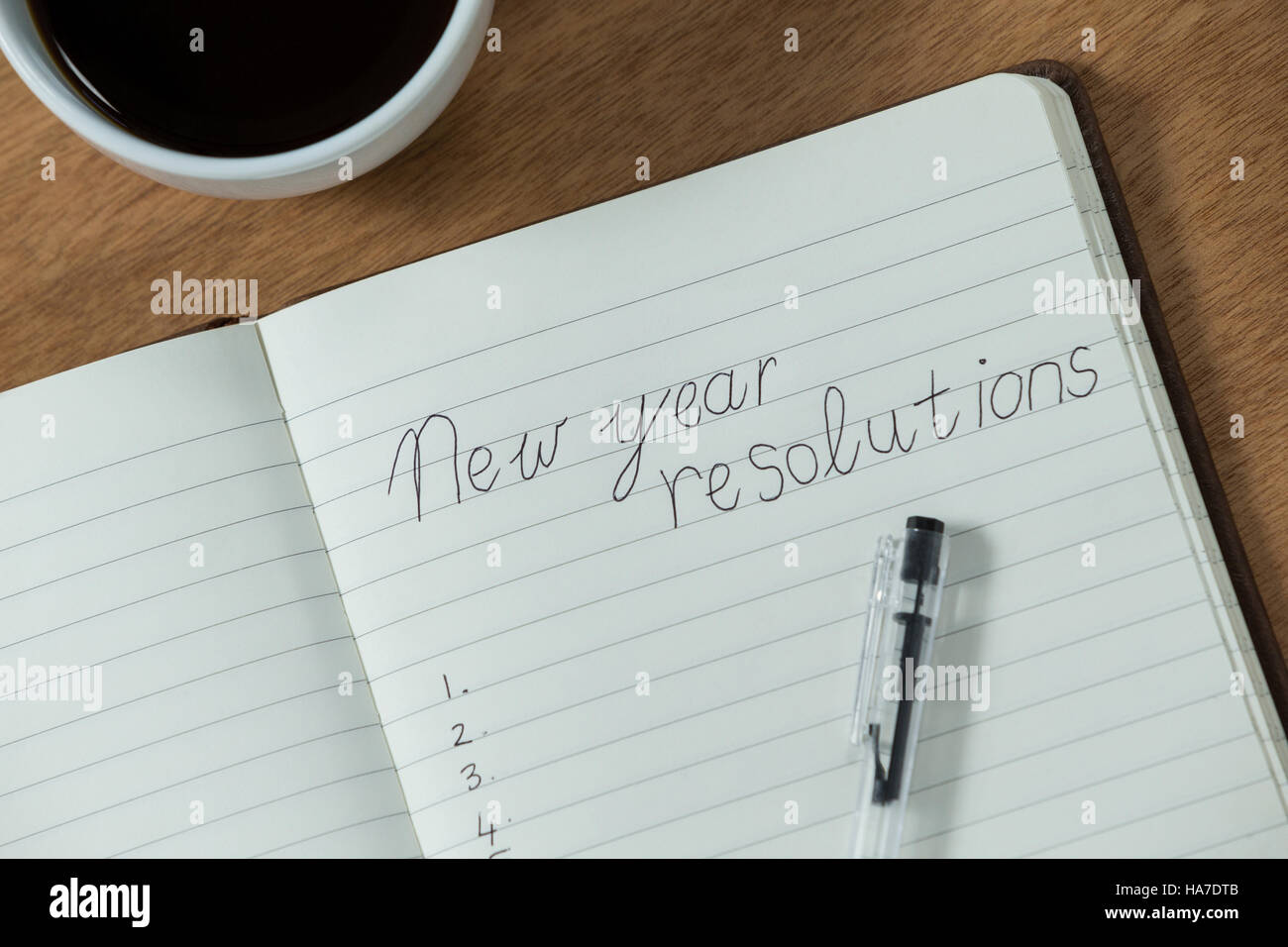 Neujahrs-Vorsätze geschrieben am Tagebuch mit Kaffeetasse Stockfoto