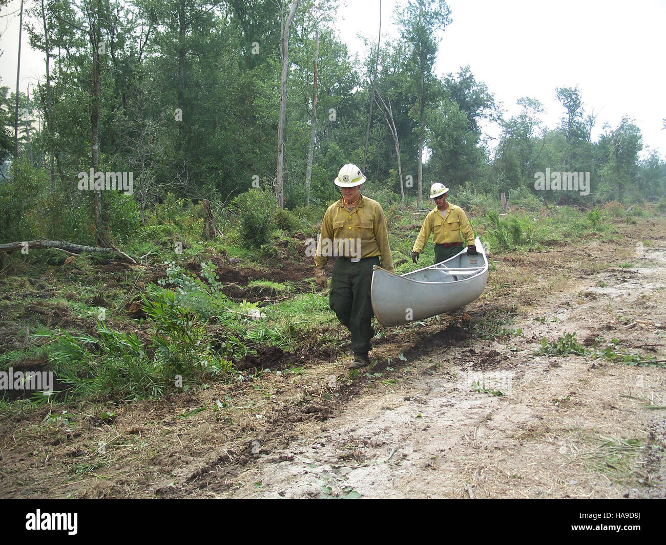 Feuerwehrleute transportieren mit einem Kanu wichtige Ausrüstungen über eine Wasserstraße, während sie auf einen Brandfall in einem Nationalpark reagieren. Diese Methode ist in Bereichen mit begrenztem Zugang zu motorisierten Fahrzeugen von entscheidender Bedeutung, um ein schnelles und effizientes Eingreifen auf Brandereignisse an entlegenen Standorten zu gewährleisten. Stockfoto