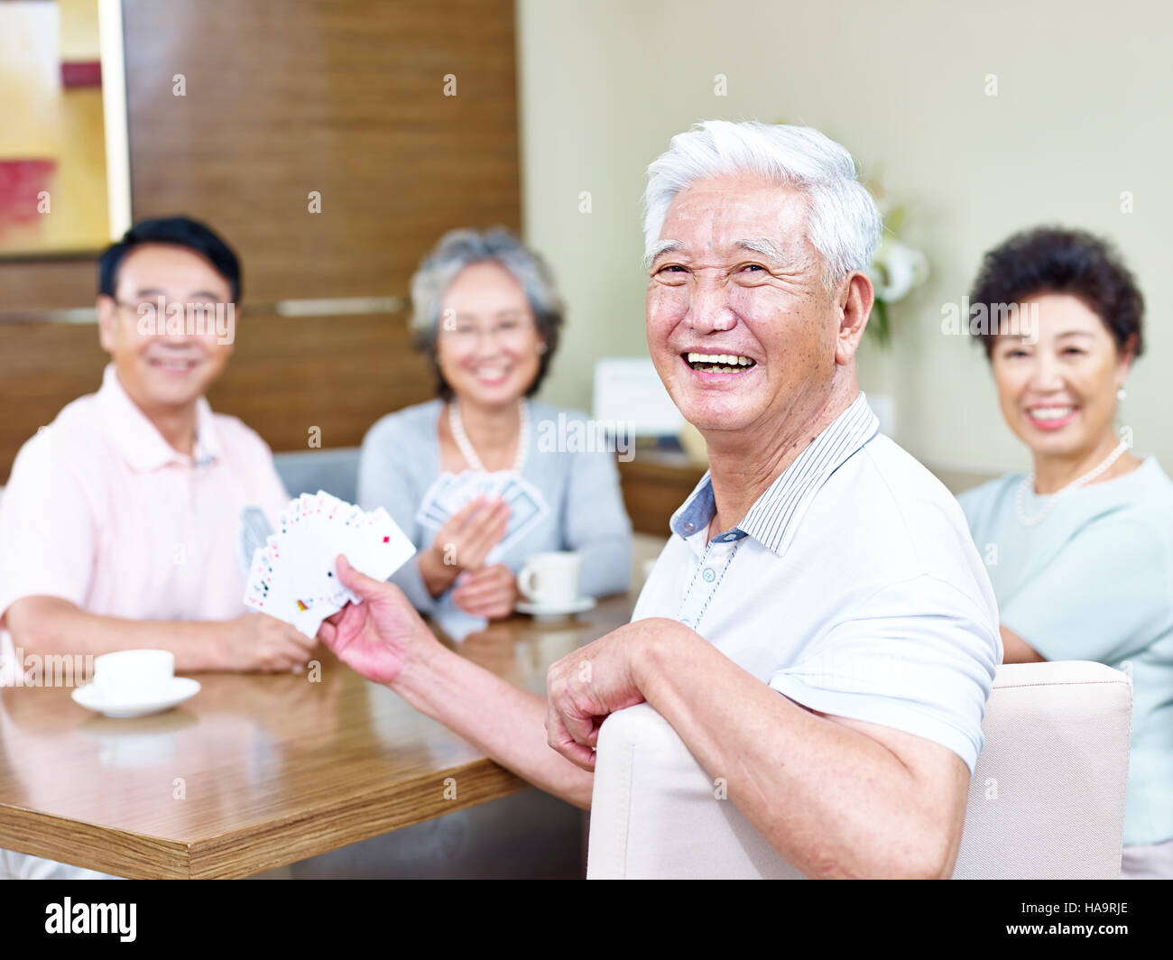 Senior asiatischen Mann Blick in die Kamera Lächeln beim Karten spielen mit Freunden. Stockfoto