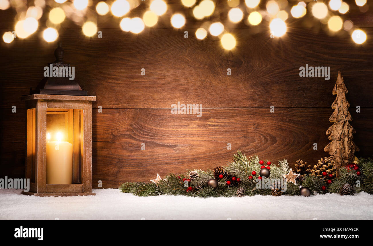 Weihnachtsszene mit einer Laterne, Ornamenten und unscharfen Lichter vor einem beleuchteten elegante dunkle Holzbrett als Textfreiraum Stockfoto
