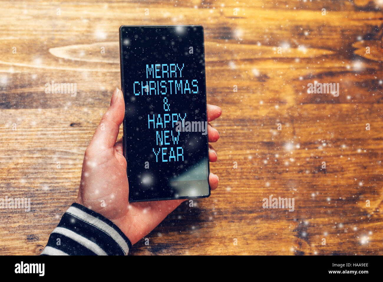 Frohe Weihnachten und ein glückliches Neujahrsbotschaft auf Handy von jungen Erwachsenen kaukasischen weibliche Person gehalten Stockfoto