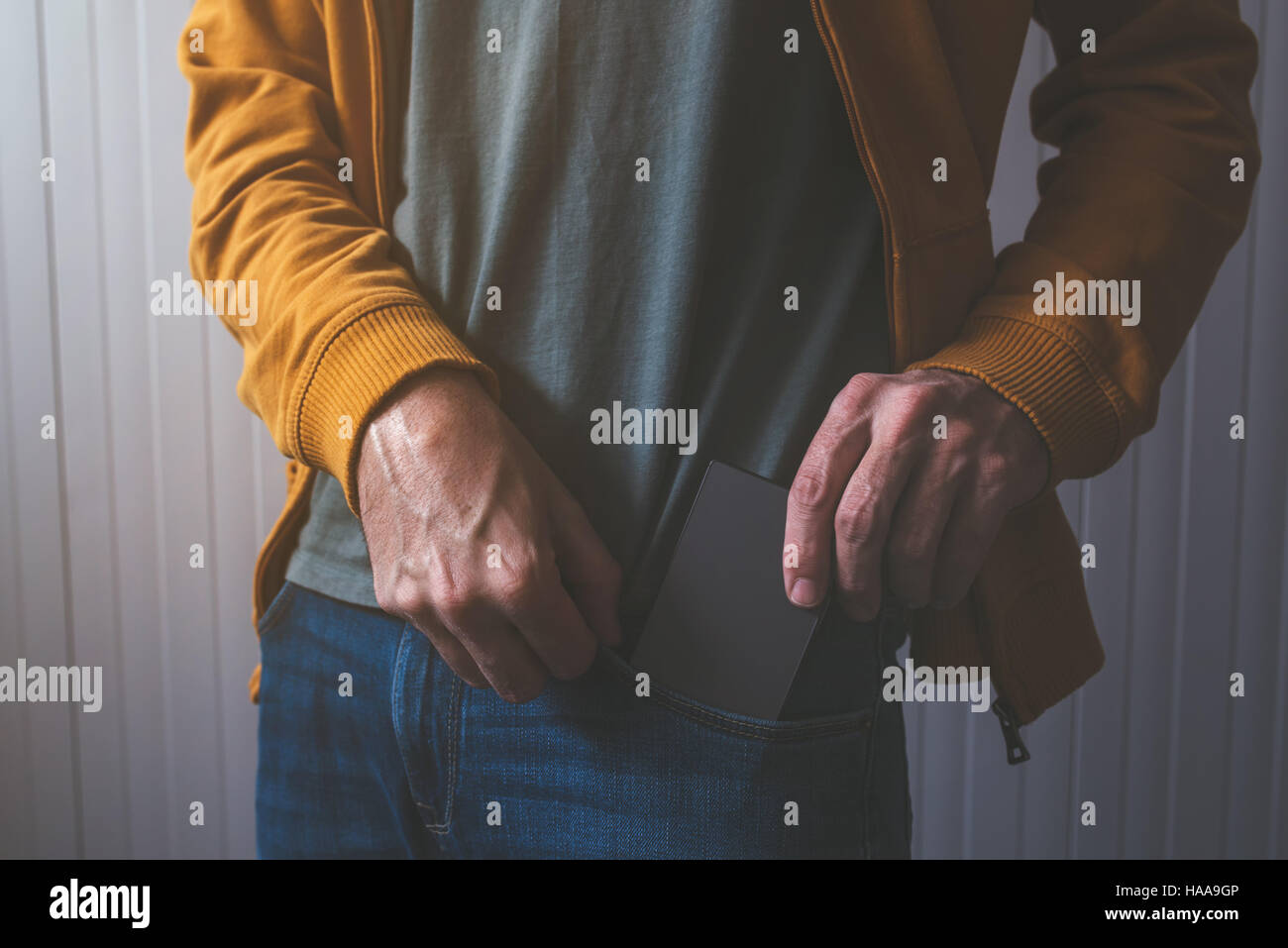 Lässige Männchen unter Smartphone-Gerät von Jeans Hosen Fronttasche Stockfoto