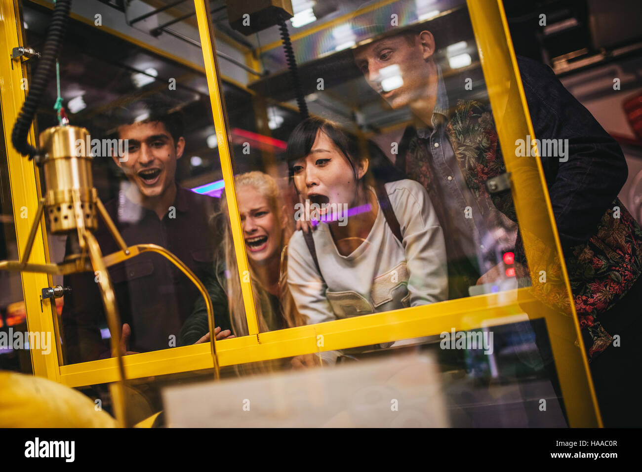 Junge Freunde spielen Spielzeug greifen Spiel im Freizeitpark begeistert. Glückliche Frau eine zufällige Stofftier in einem Automaten auswählen. Stockfoto