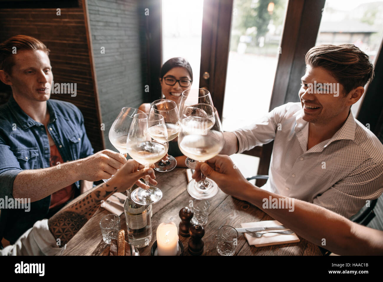 Innenaufnahme von jungen Freunden Toasten mit einem Glas Wein in einem Restaurant. Gruppe von Männern und Frauen genießen ein Abendessen im Restaurant. Stockfoto