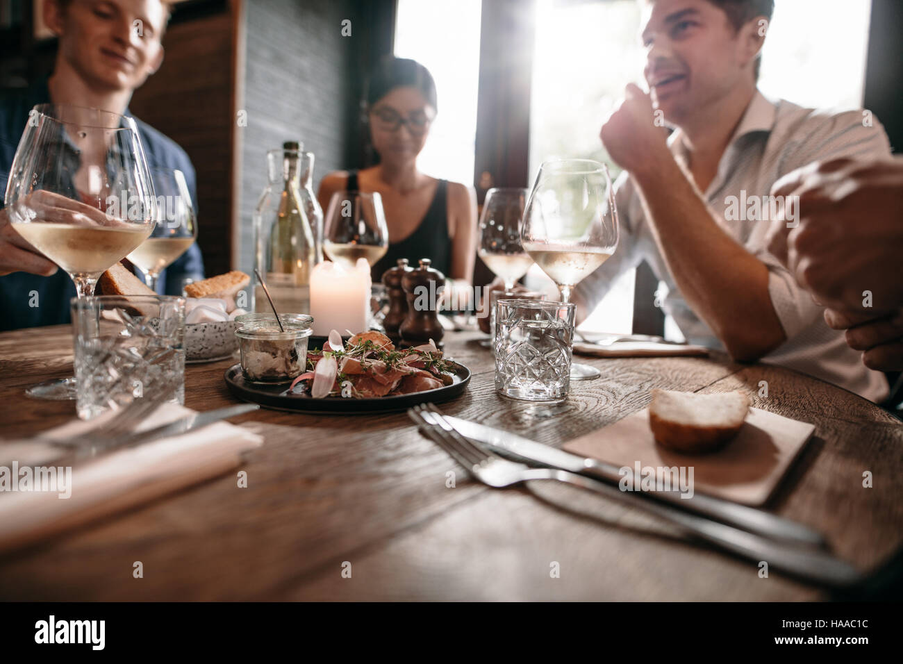 Gruppe von Freunden treffen im Café mit Gläser Wein am Tisch. Männer und Frauen, die ein Abendessen im Restaurant. Stockfoto