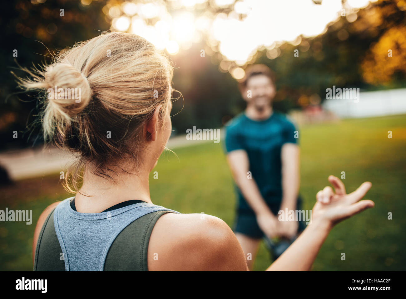 Rückansicht Schuss der Frau an der Park-Mann Training mit Kettlebell im Hintergrund. Stockfoto