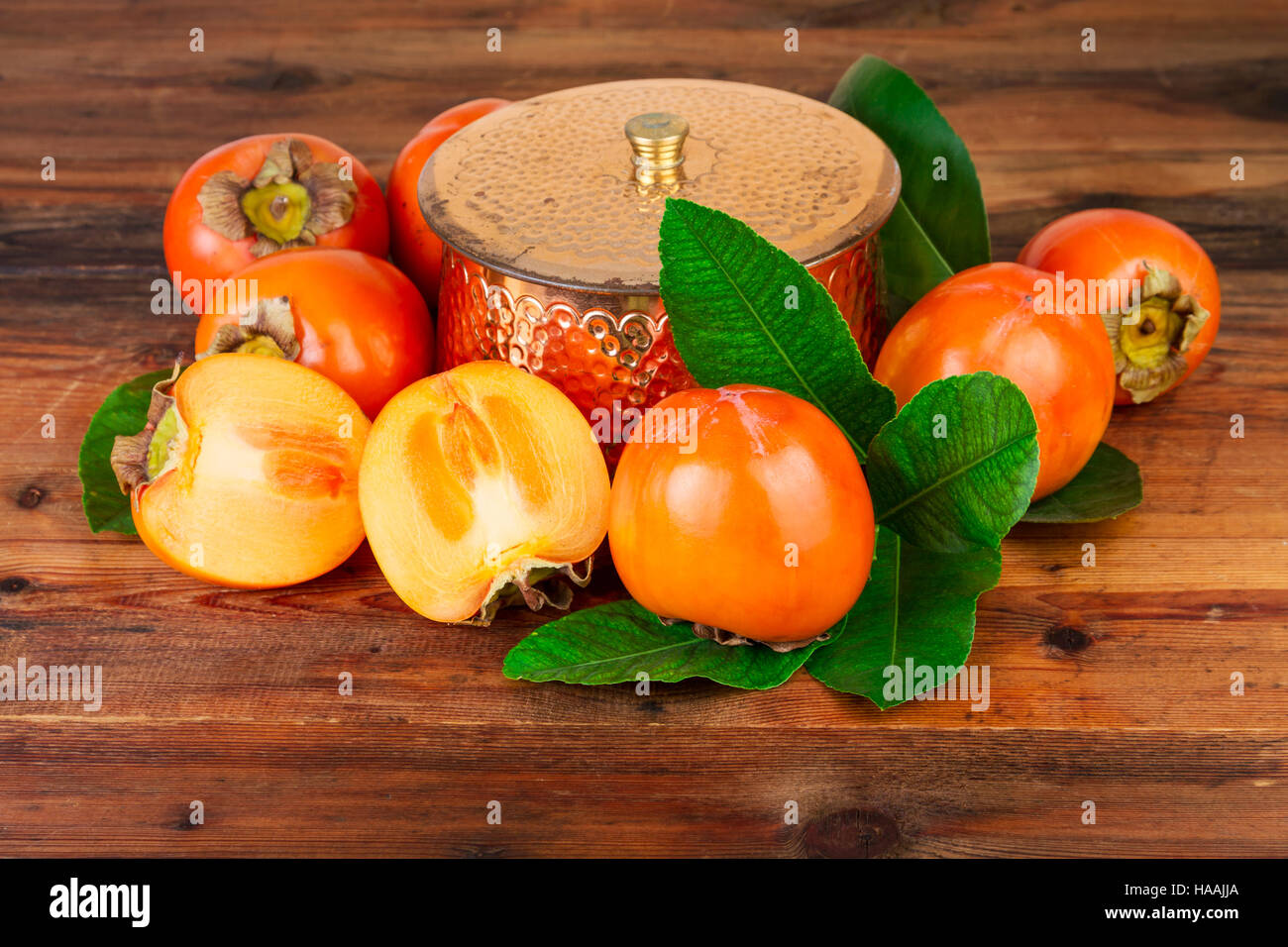 Kaki mit Kupfer Vase auf altem Holz. Oriental Osten Stillleben. Stockfoto