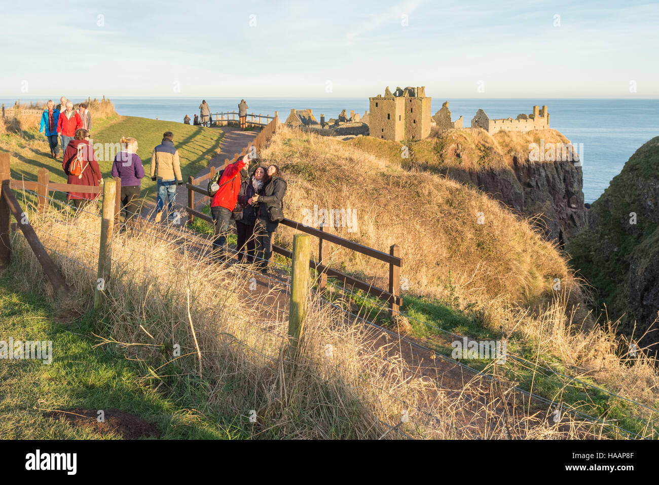 Dunnottar Castle, Stonehaven, Schottland - Besucher genießen den Winter Sonnenuntergang Stockfoto