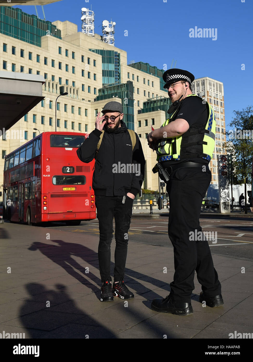 Ein Polizist spricht ein Pendler vor der Secret Intelligence Service, Gebäude, das Hauptquartier des MI6, Vauxhall Busbahnhof in Süd-London, um die Einführung des Anti-Terror-Patrouille Polizeieinheiten quer durch die Hauptstadt zu markieren. Stockfoto